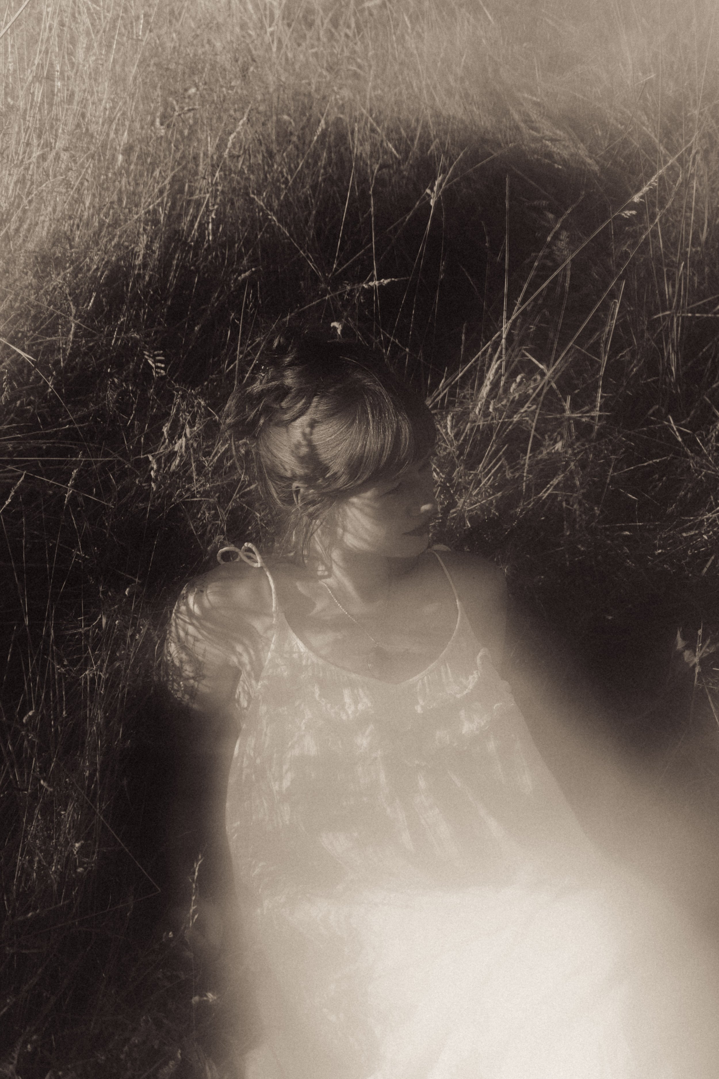 A woman with long hair lying in tall grass.