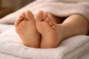 Close-up of someone's bare feet resting on a bed.