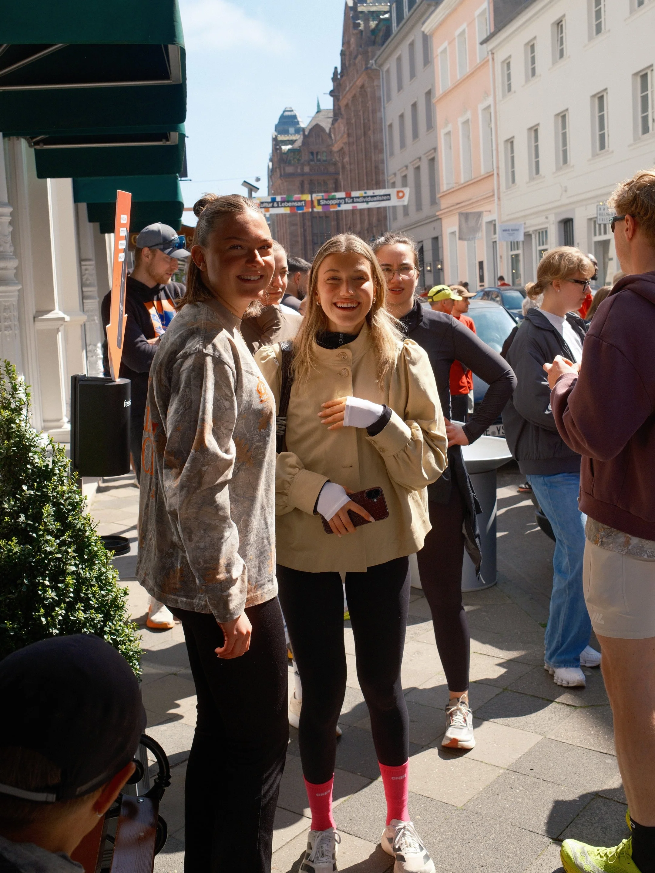 Gruppe junger Menschen steht auf einer Straße, lächelt und unterhält sich an einem sonnigen Tag in der Stadt