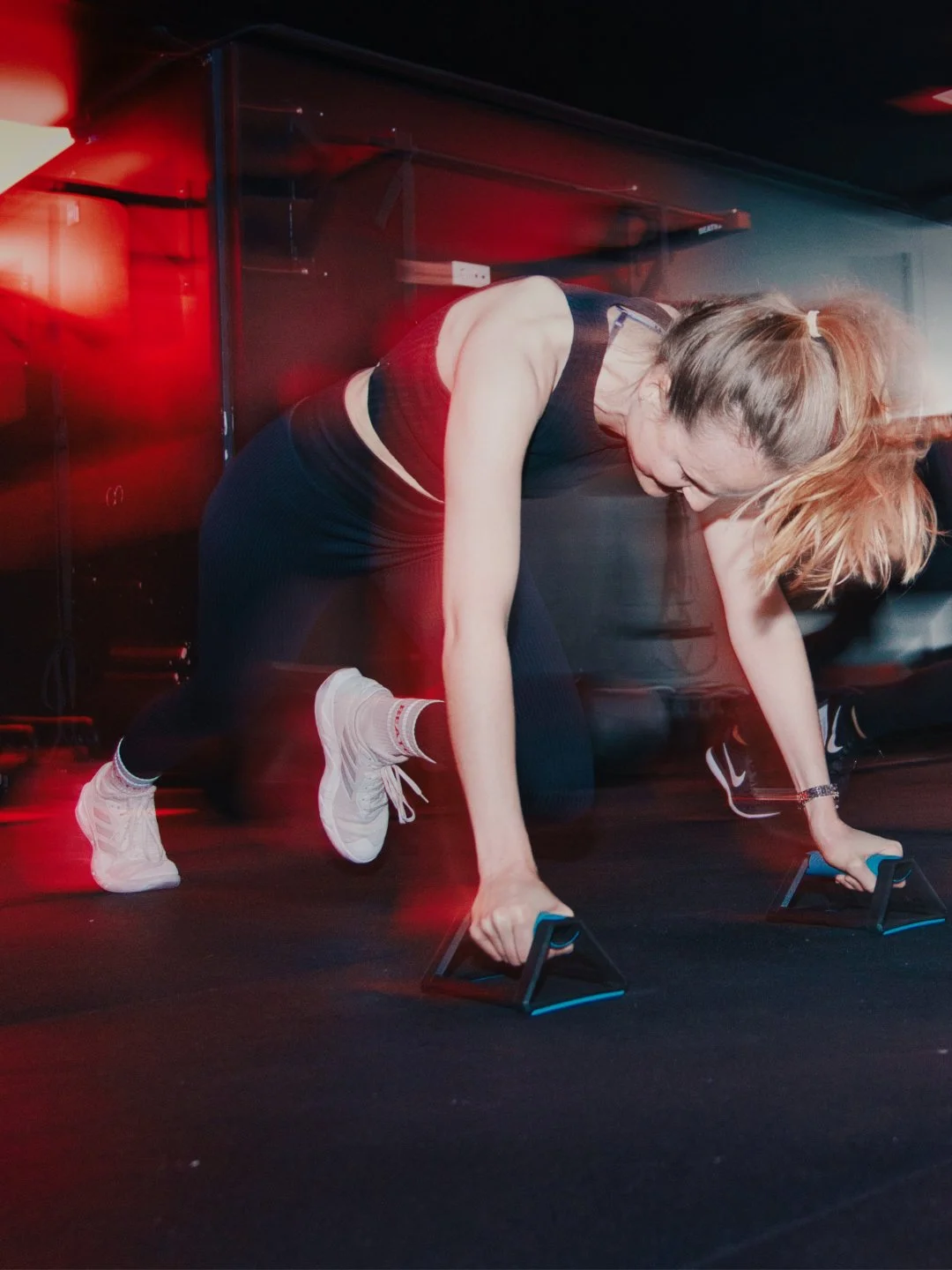 Frau beim Workout im Fitnessstudio, Ausführung von Liegestützen mit Handstützen