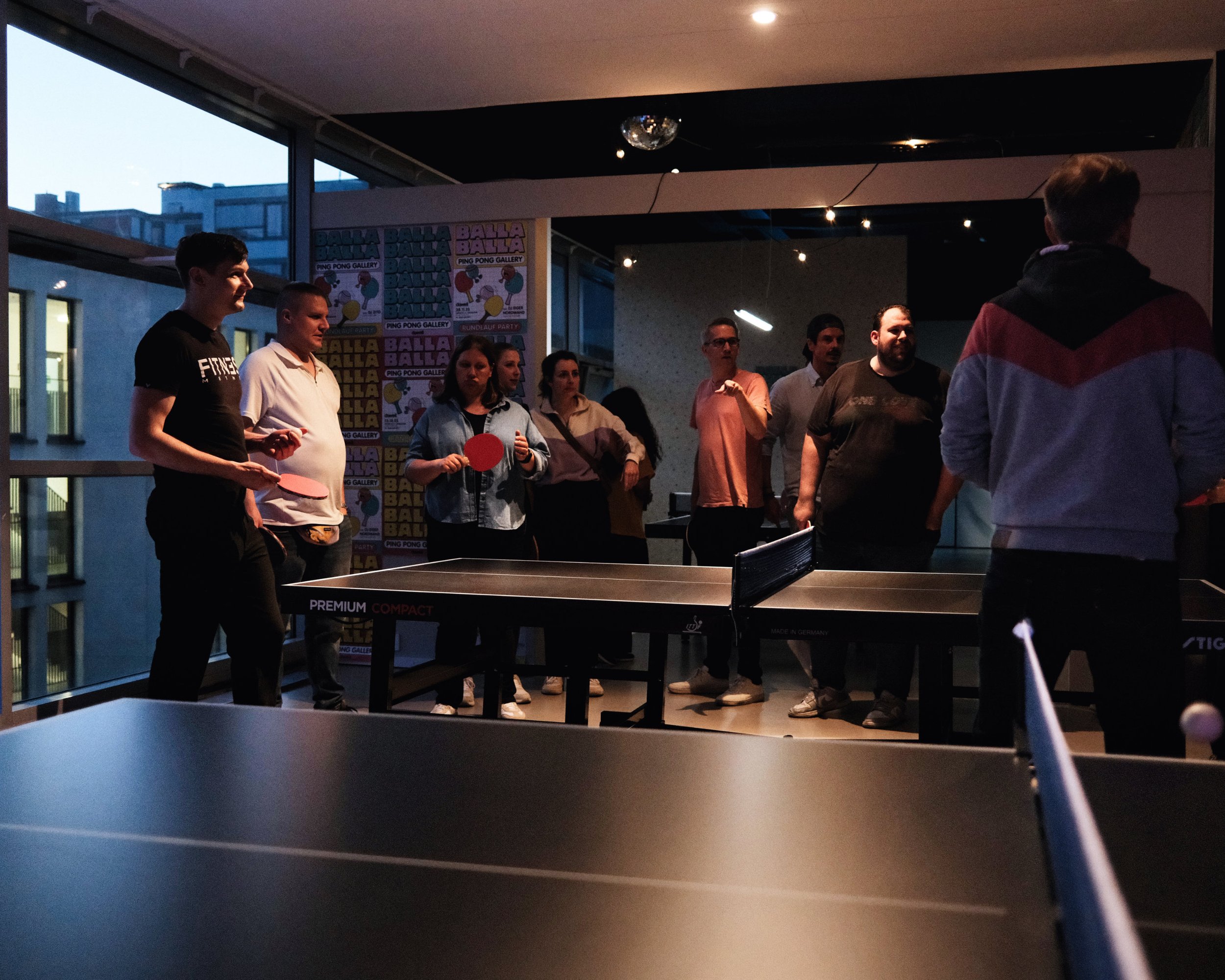 Eine Gruppe von Menschen steht in einem Raum und spielt Tischtennis