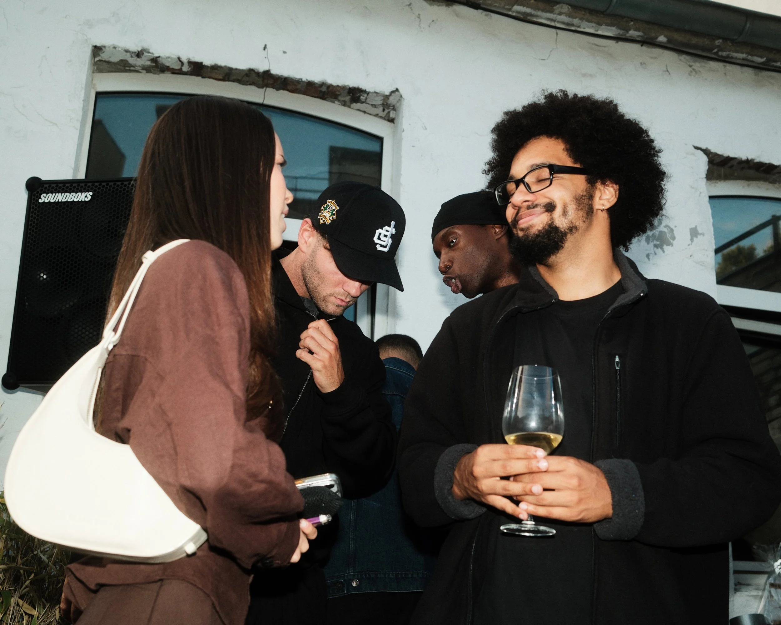 Menschen bei einer geselligen Zusammenkunft, eine Person hält ein Glas Weißwein