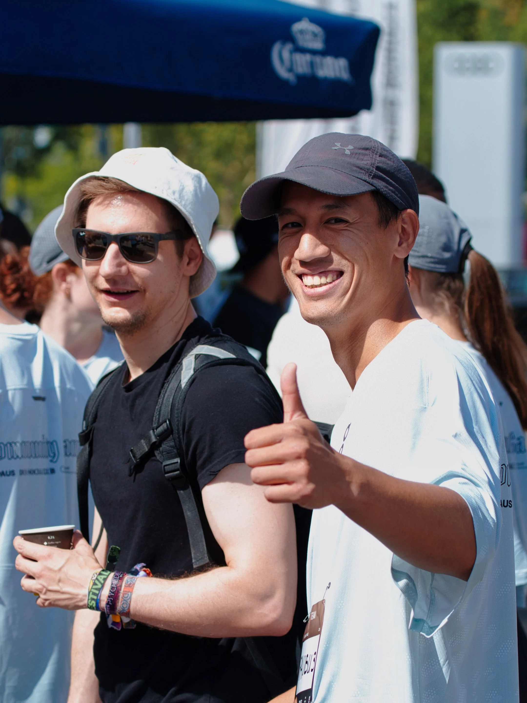 Zwei lachende junge Männer bei einem öffentlichen Event, einer gibt einen Daumen hoch