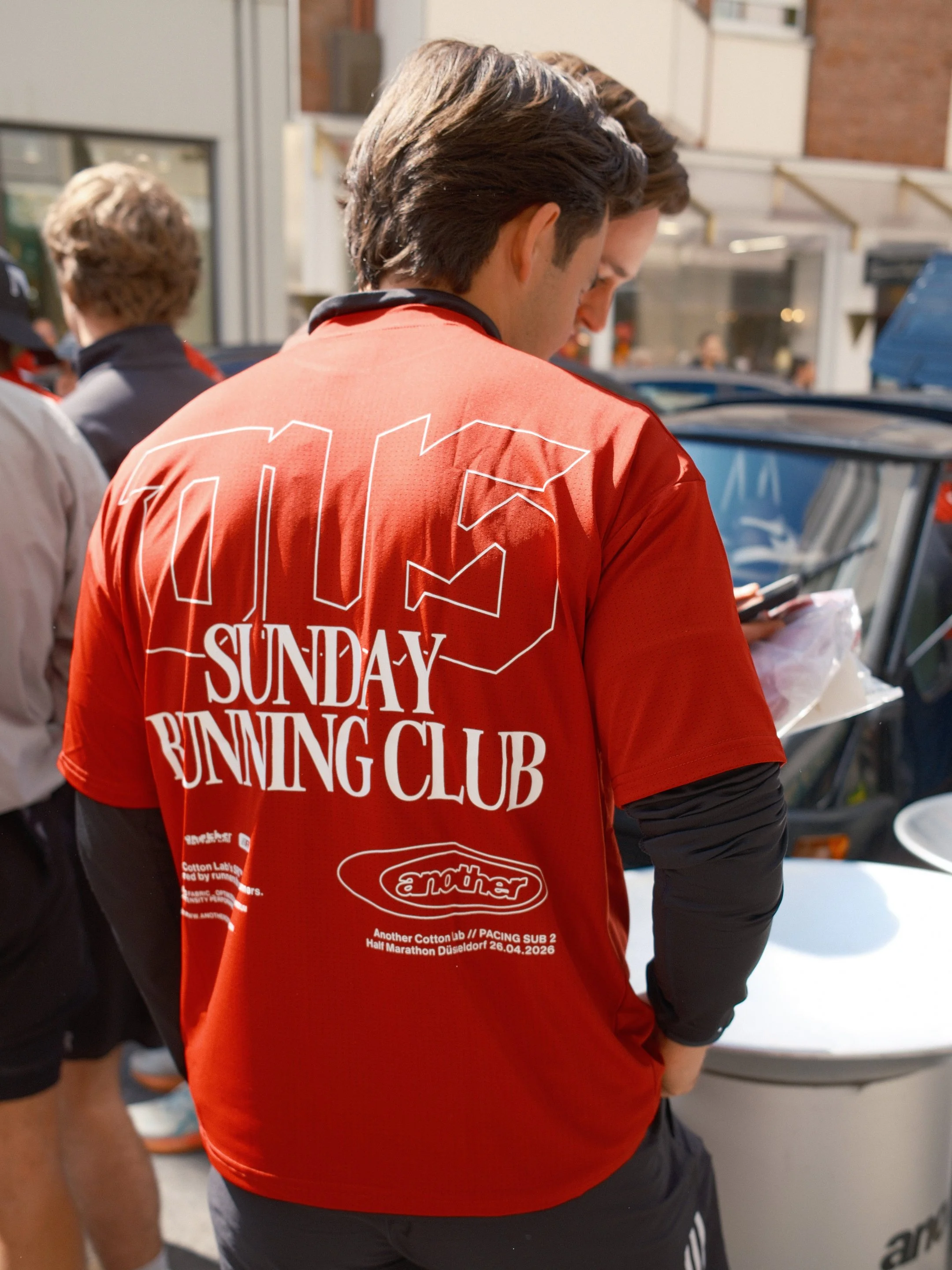 Ein Mann trägt ein rotes T-Shirt mit Schriftzug 'Sunday Rumming Club' während er an einem Event teilnimmt