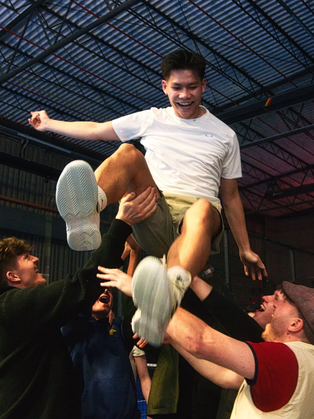 Menschen feiern und heben eine lachende Person in die Luft, in einem Indoor-Eventraum