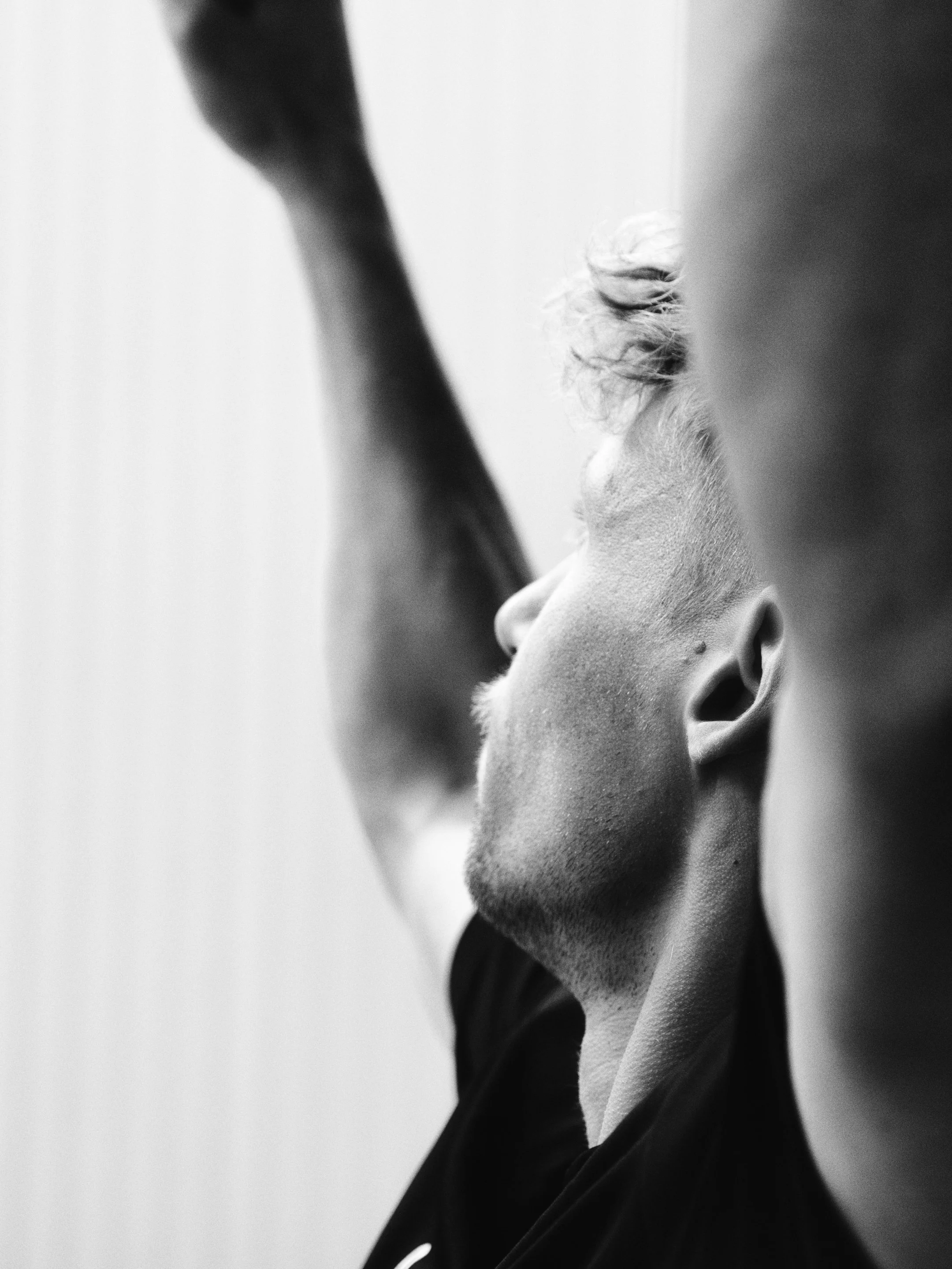 Schwarz-weiß-Fotografie eines Mannes, der nach oben blickt, mit einem Arm in die Luft gestreckt