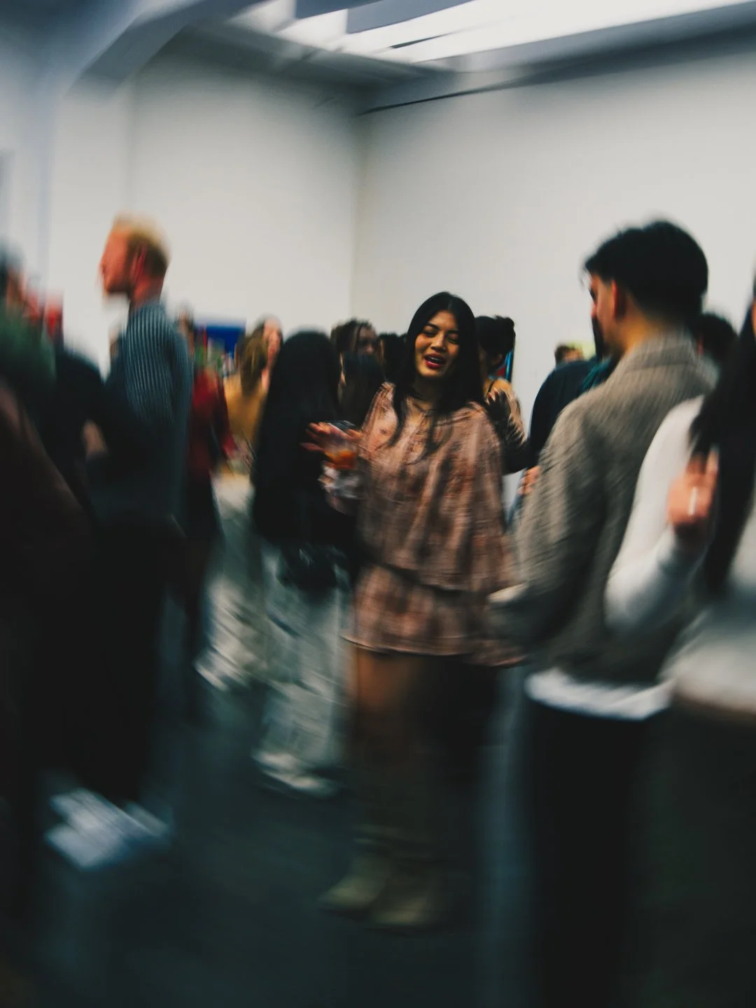 Menschen auf einer Party oder Veranstaltung, einige im Gespräch, eine Person in der Mitte hält ein Getränk, die Szene ist lebhaft und ungeordnet
