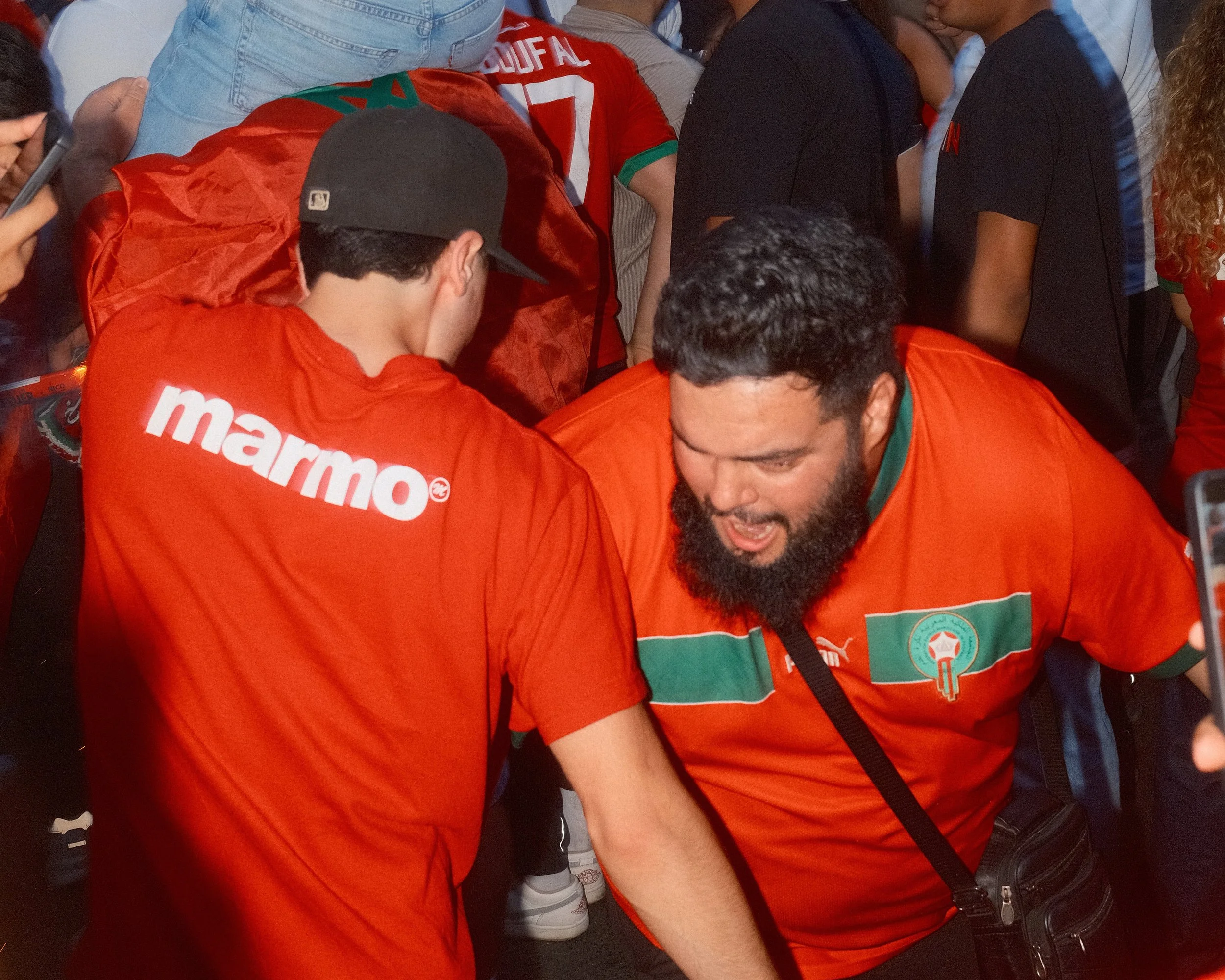 Mehrere Menschen in roten und schwarzen T-Shirts versammelt, vermutlich bei einem öffentlichen Ereignis oder Sportveranstaltung