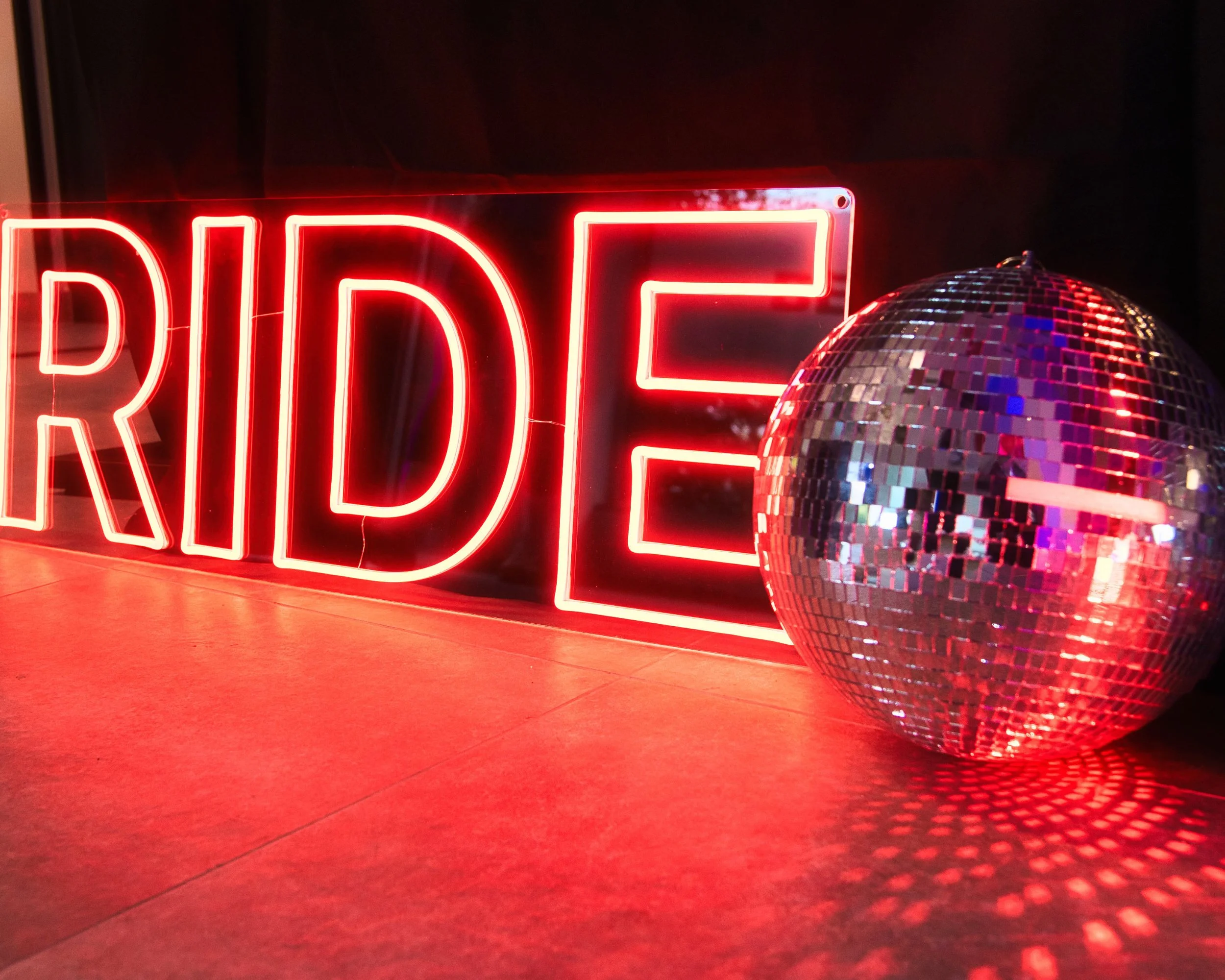 Ein rotes Neon-Schild mit der Aufschrift »DANCE« und eine Disco-Kugel davor
