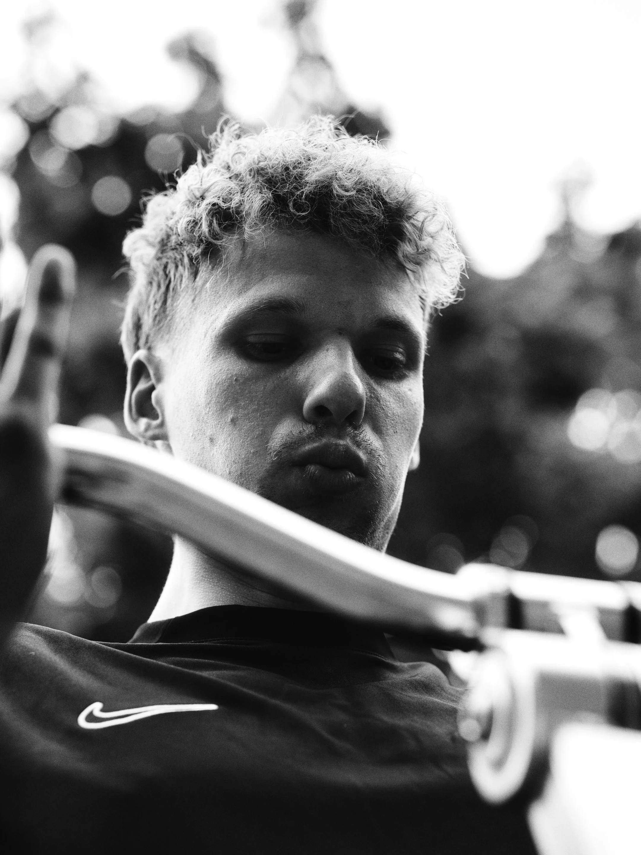 Schwarz-weiß-Fotografie eines jungen Mannes mit lockigem Haar, der einen Handschuh trägt und nach unten schaut