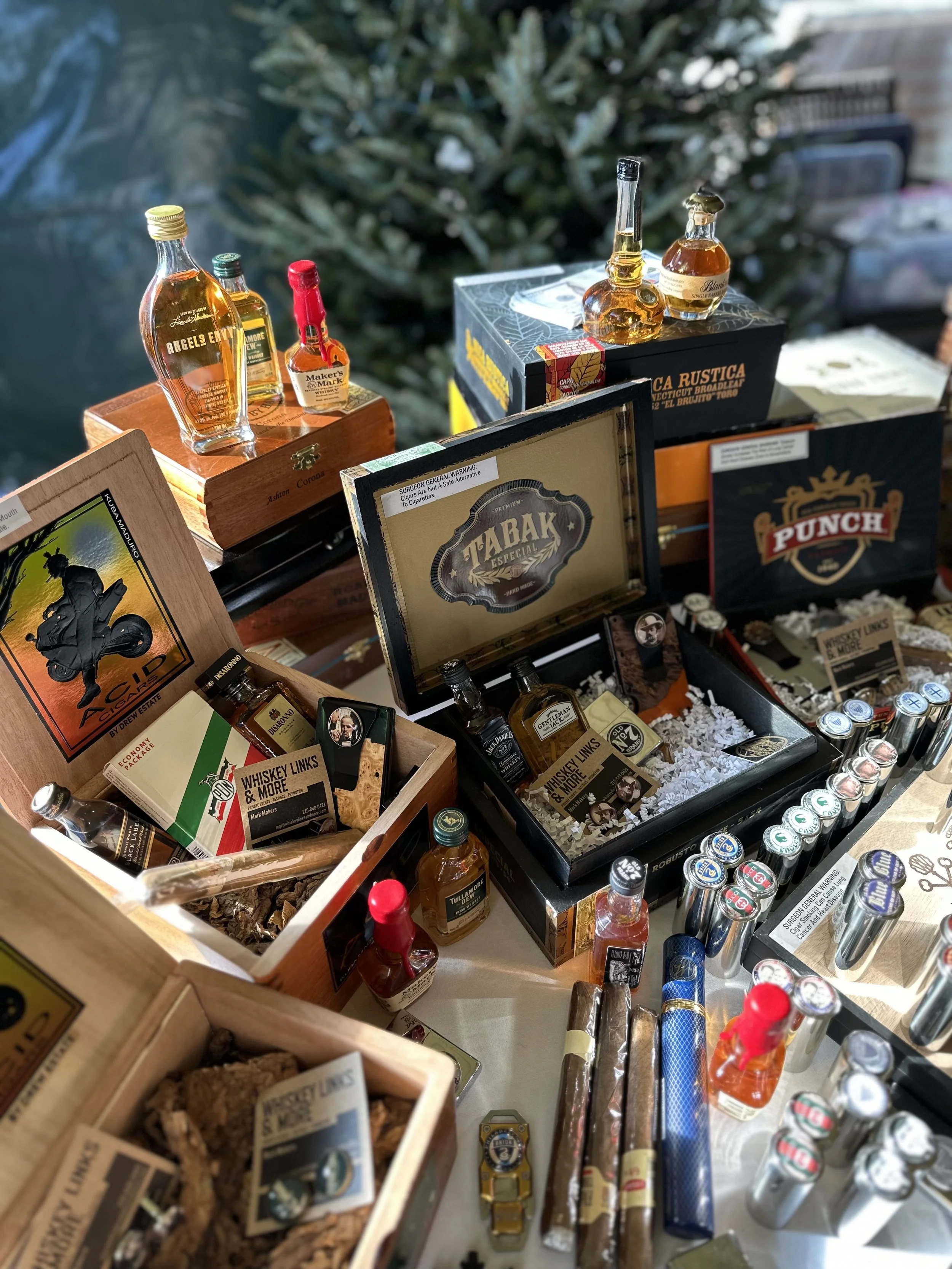 Display of miniature bottles of whiskey, cigars, and related accessories on a table at an event or store.