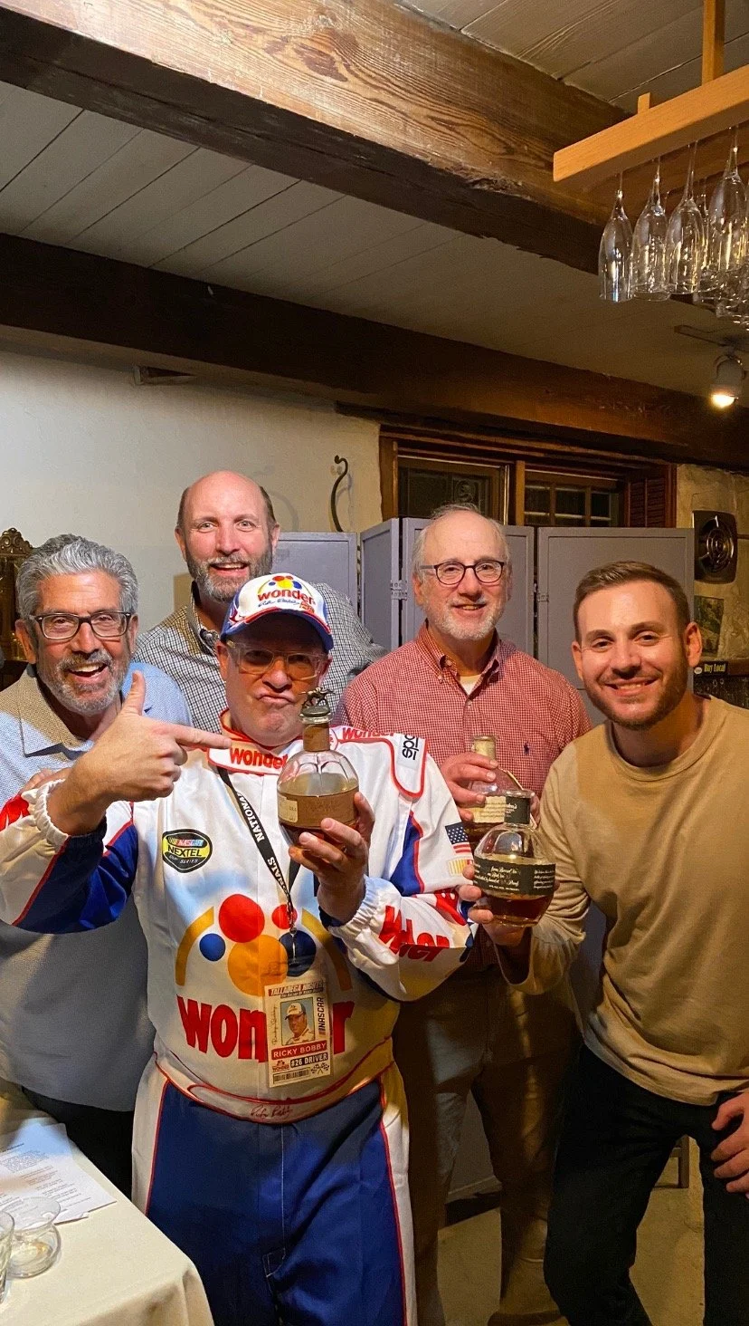Mark Makers posing with members of the whiskey club smiling at an event