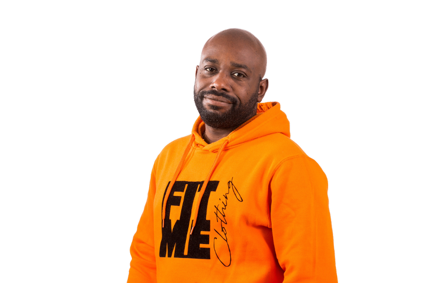 Man with a shaved head and beard wearing an orange hoodie with black text.
