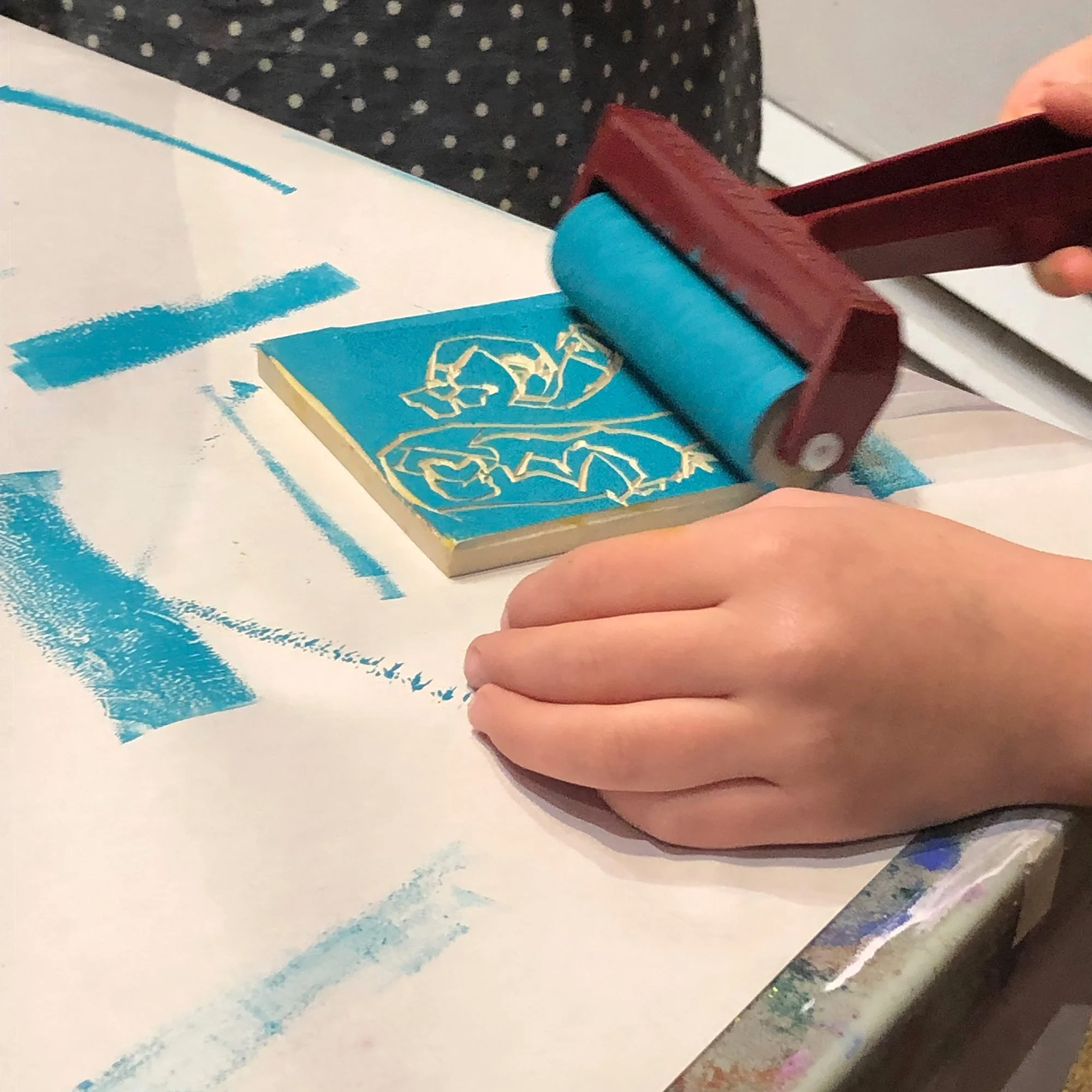 Child rolling paint onto a printmaking block