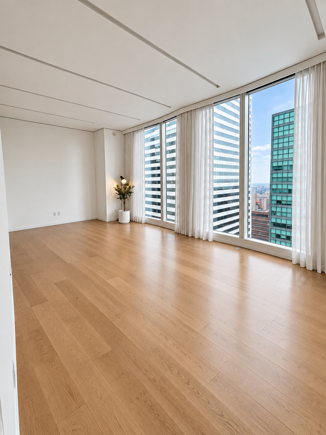 Empty modern apartment with hardwood floors and large windows.