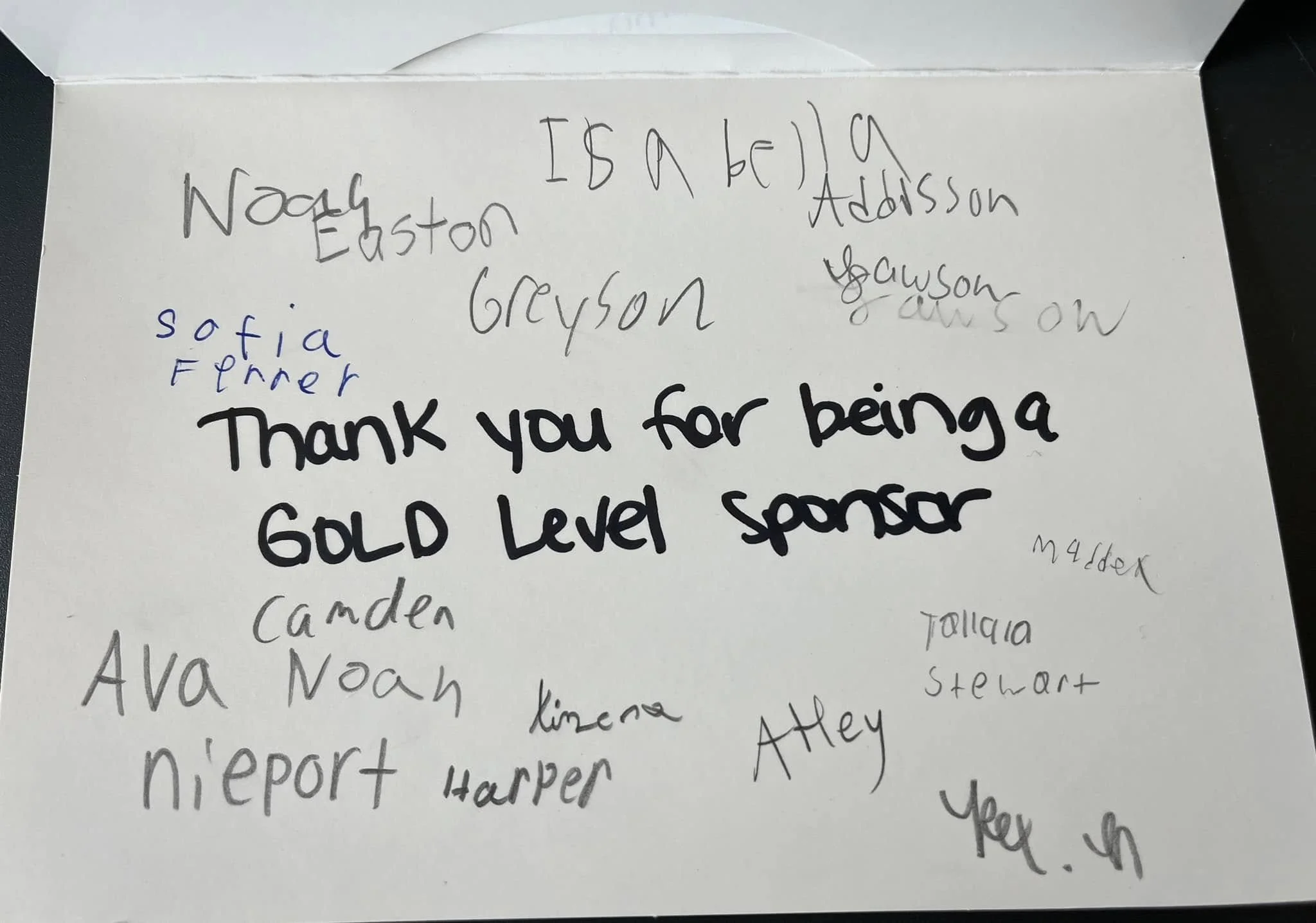 A handwritten note on white paper with list of coffee shop locations and a message that says 'Thank you for being a gold level sponsor'.