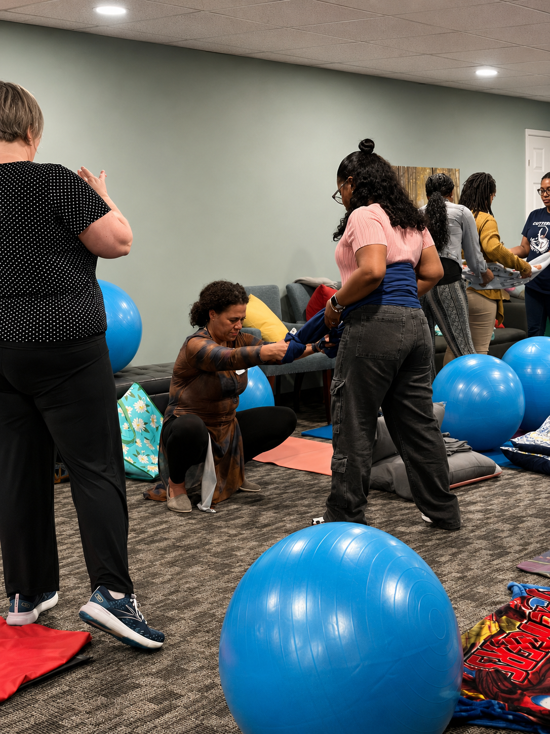 Group of women participating in a doula workshop, with exercise balls, mats.