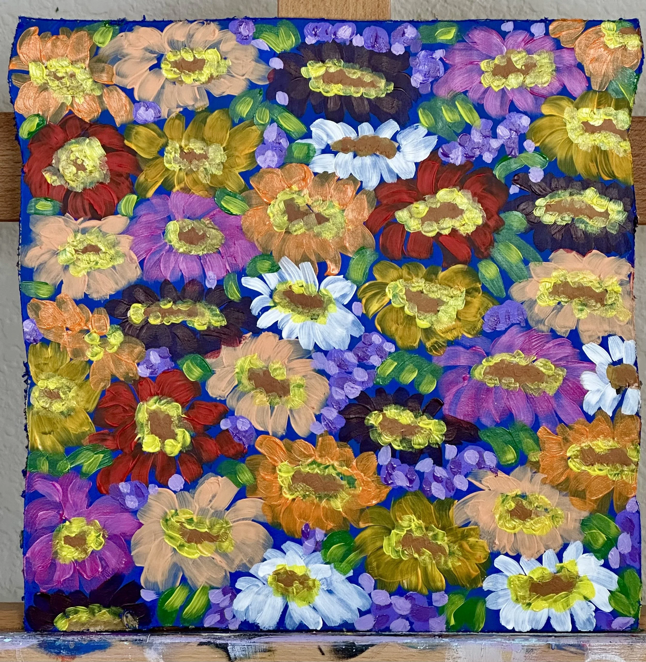 Multi color zinnias on a blue background painted on cardboard.