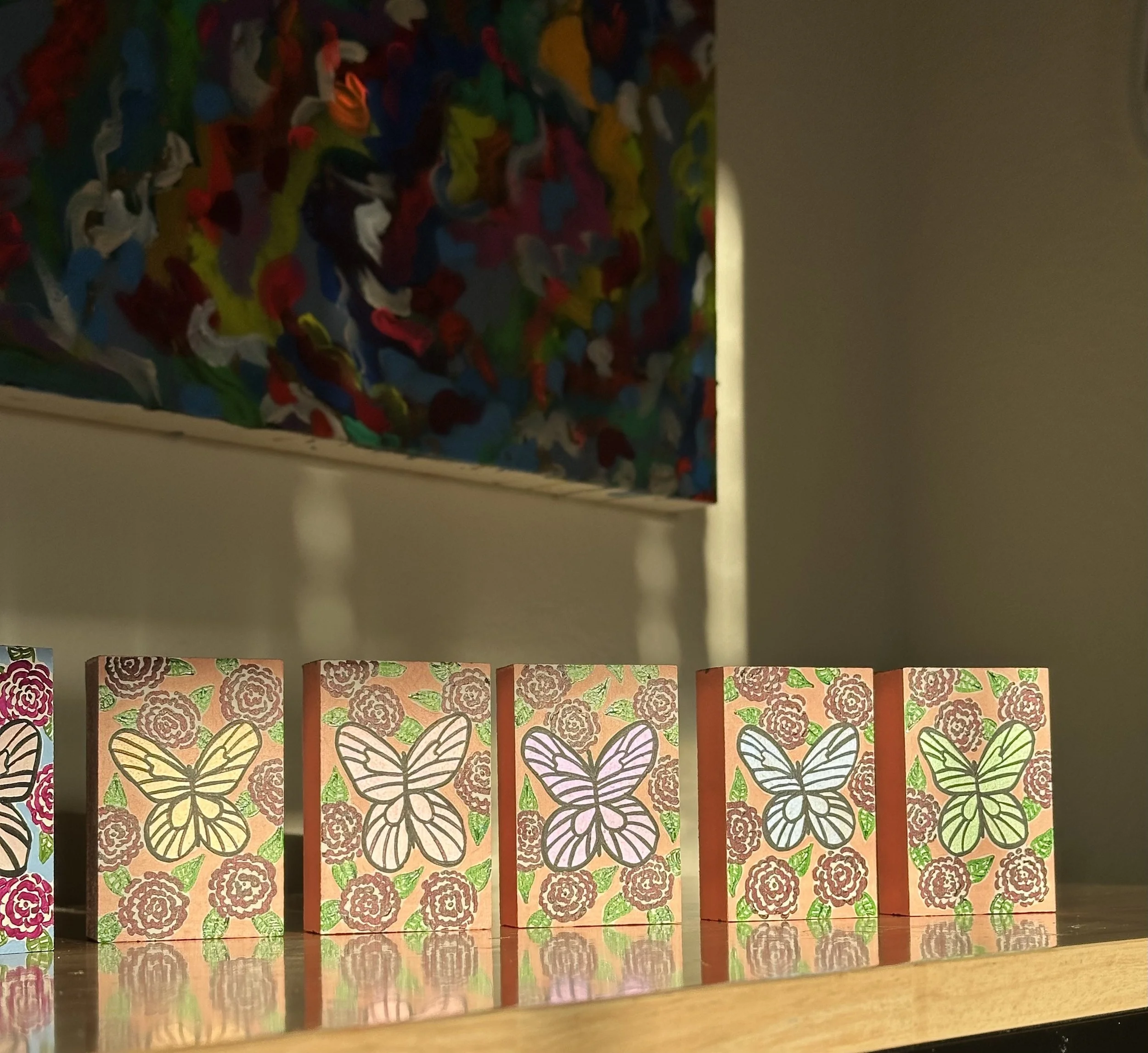 Purple, red, orange, blue and green iridescent butterflies on blue and pink backgrounds.