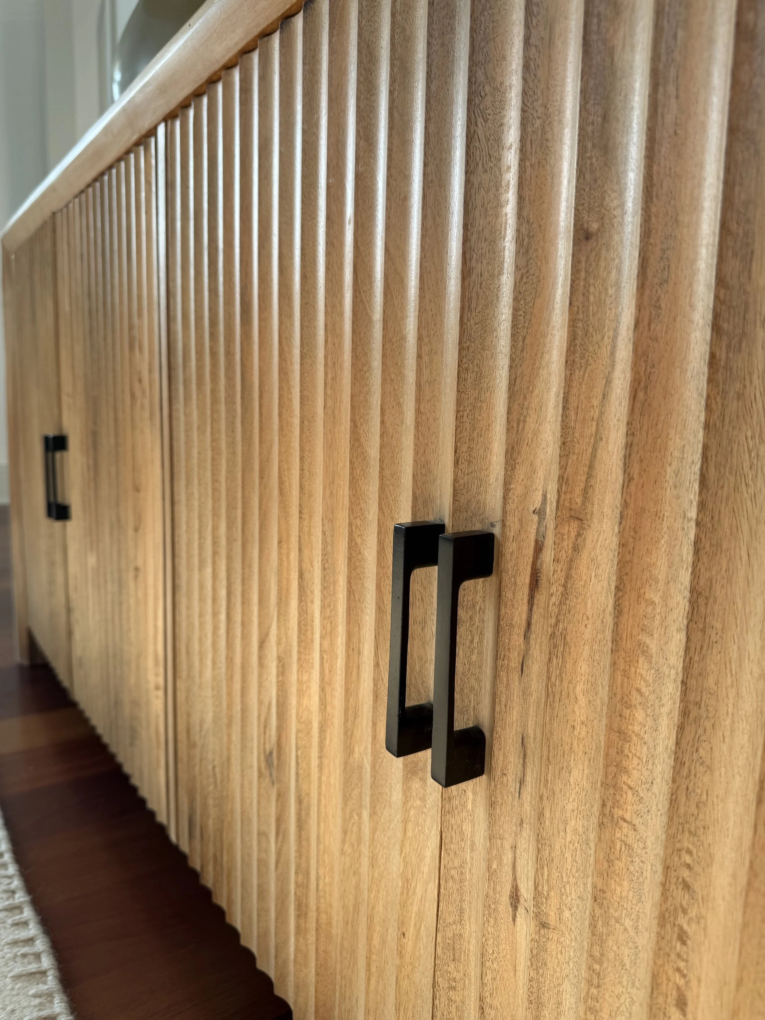 Wooden cabinet with vertical slats and black metal handles.