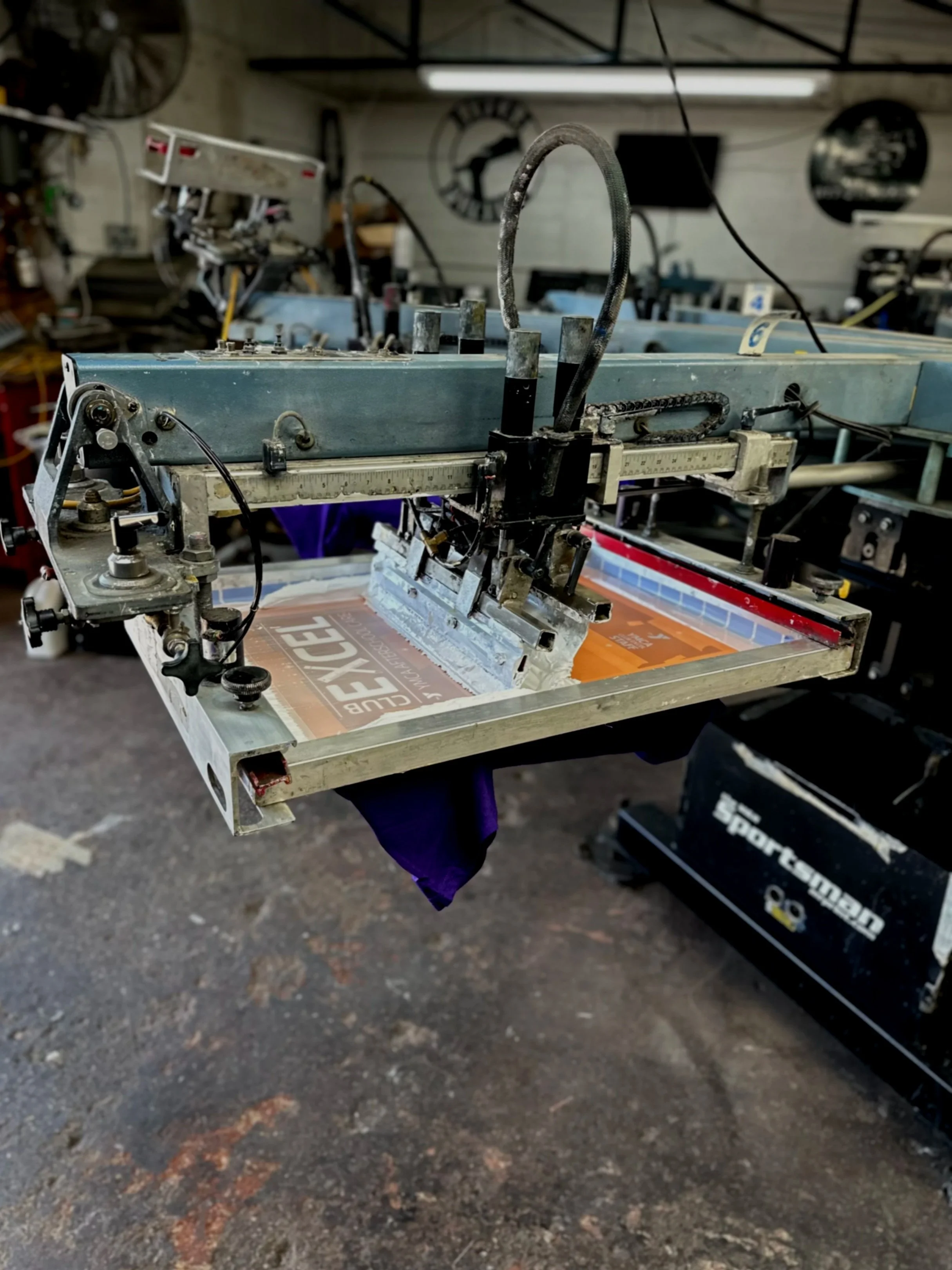 An automatic screen printing press printing shirts for a local organization.