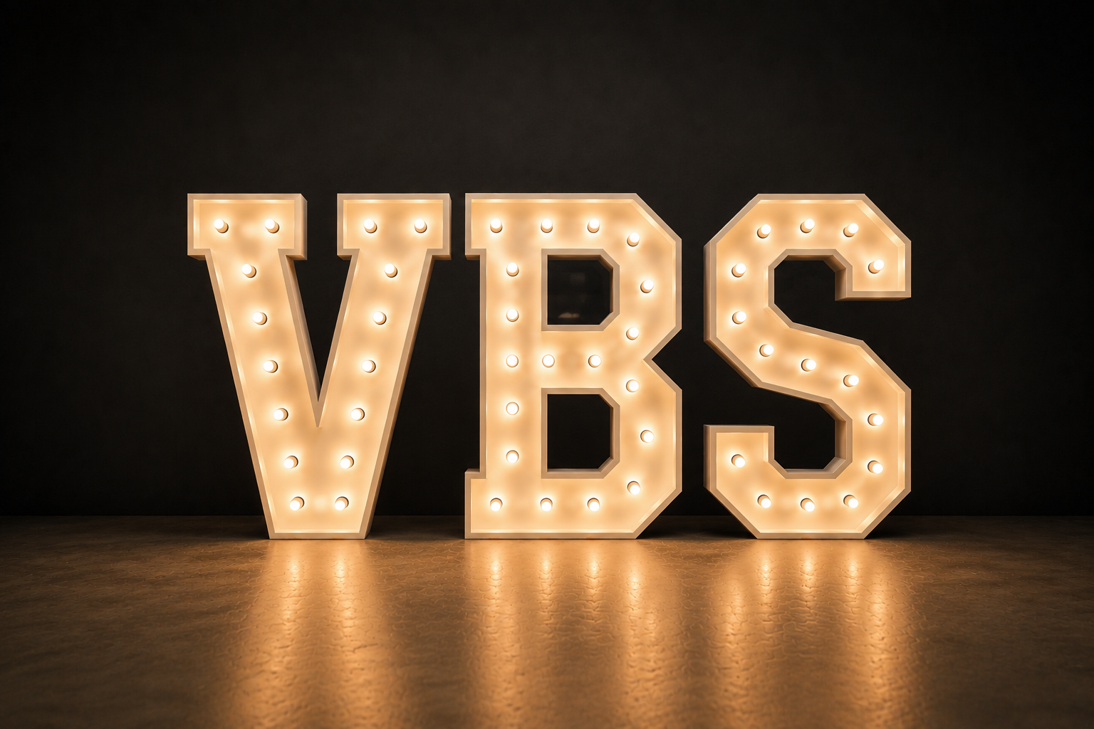 Large illuminated marquee letters spelling 'VBS' on a dark background with reflections on the floor.