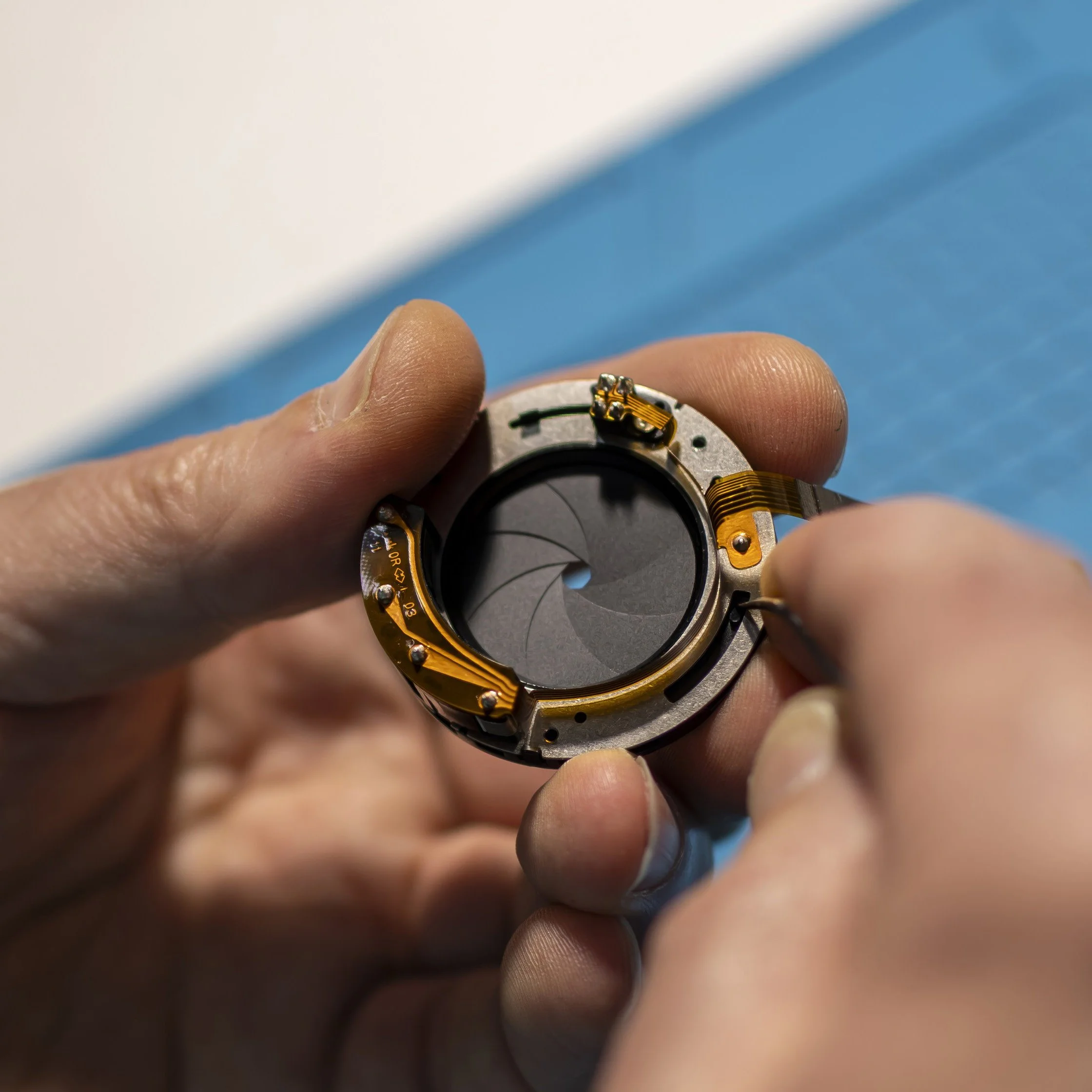 The aperture mechanism reveals just how delicate the engineering inside a lens can be. Carefully inspecting its tiny blades and connections requires a steady hand, a trained eye and an understanding of how precision mechanics and electronics work tog