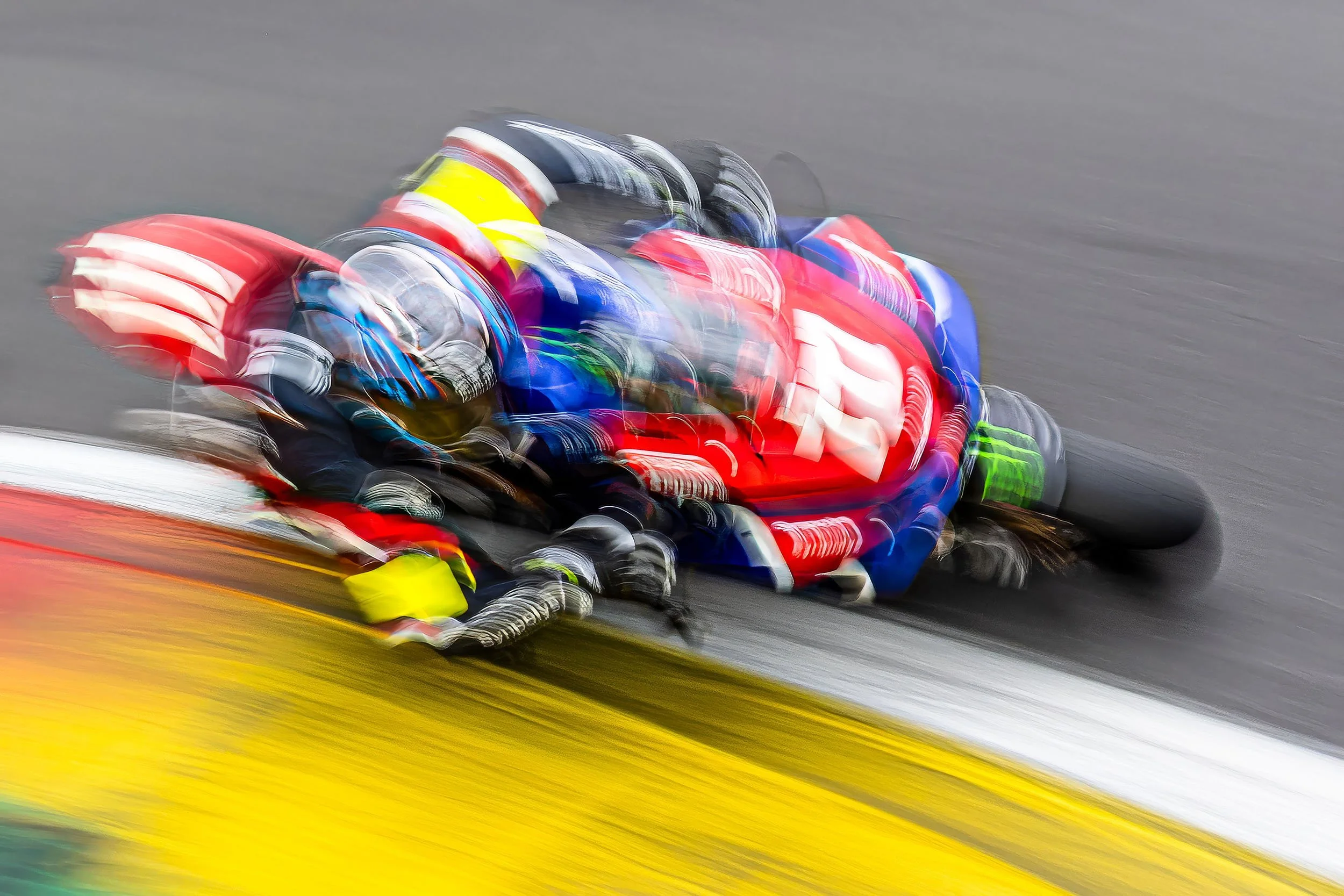 Blurred action photo of race cars and drivers on a racetrack, showing motion and speed.