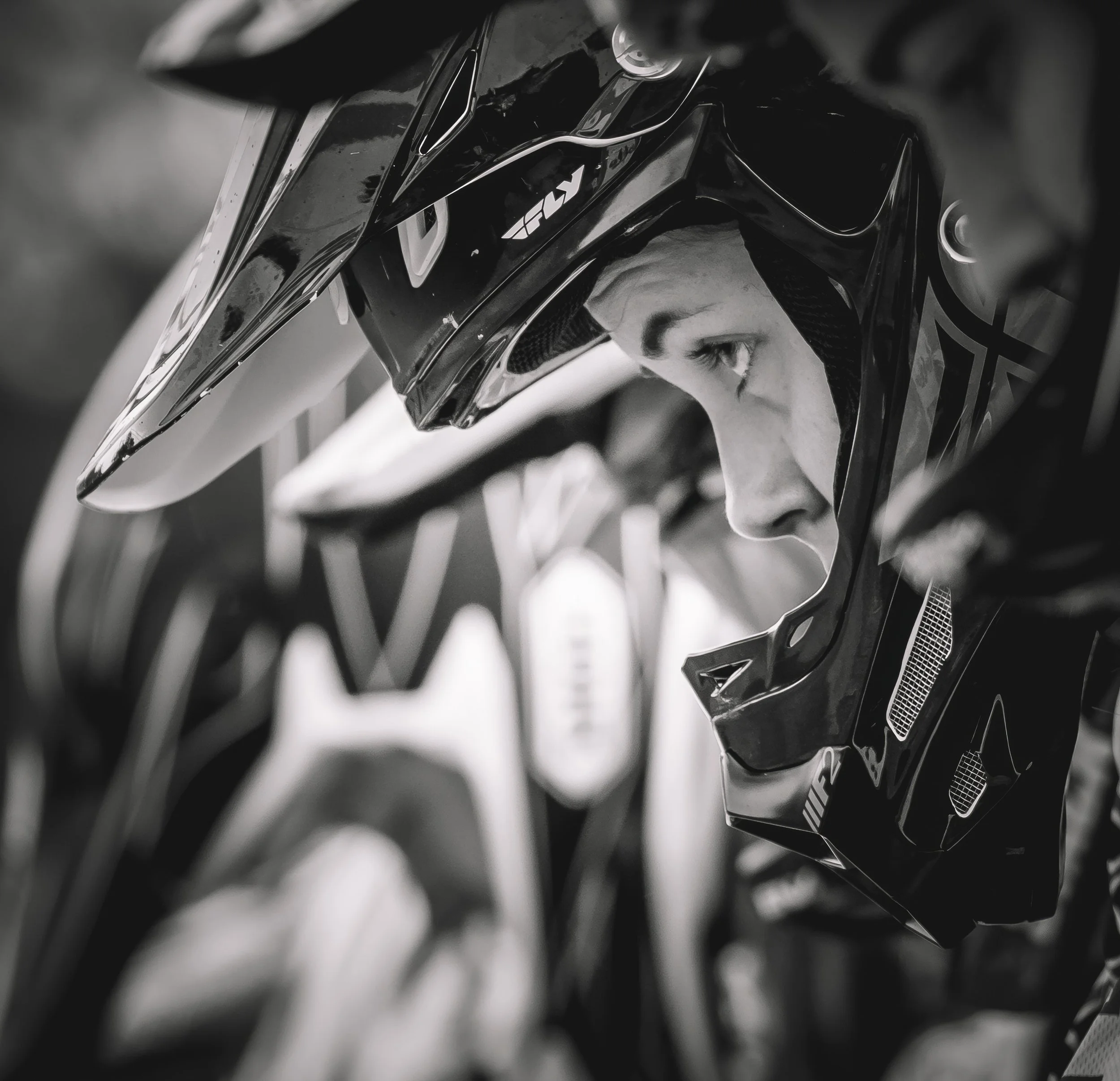 Close-up of a black motorcycle helmet with the logo 'FOX' on it, reflecting light, with a blurred background.