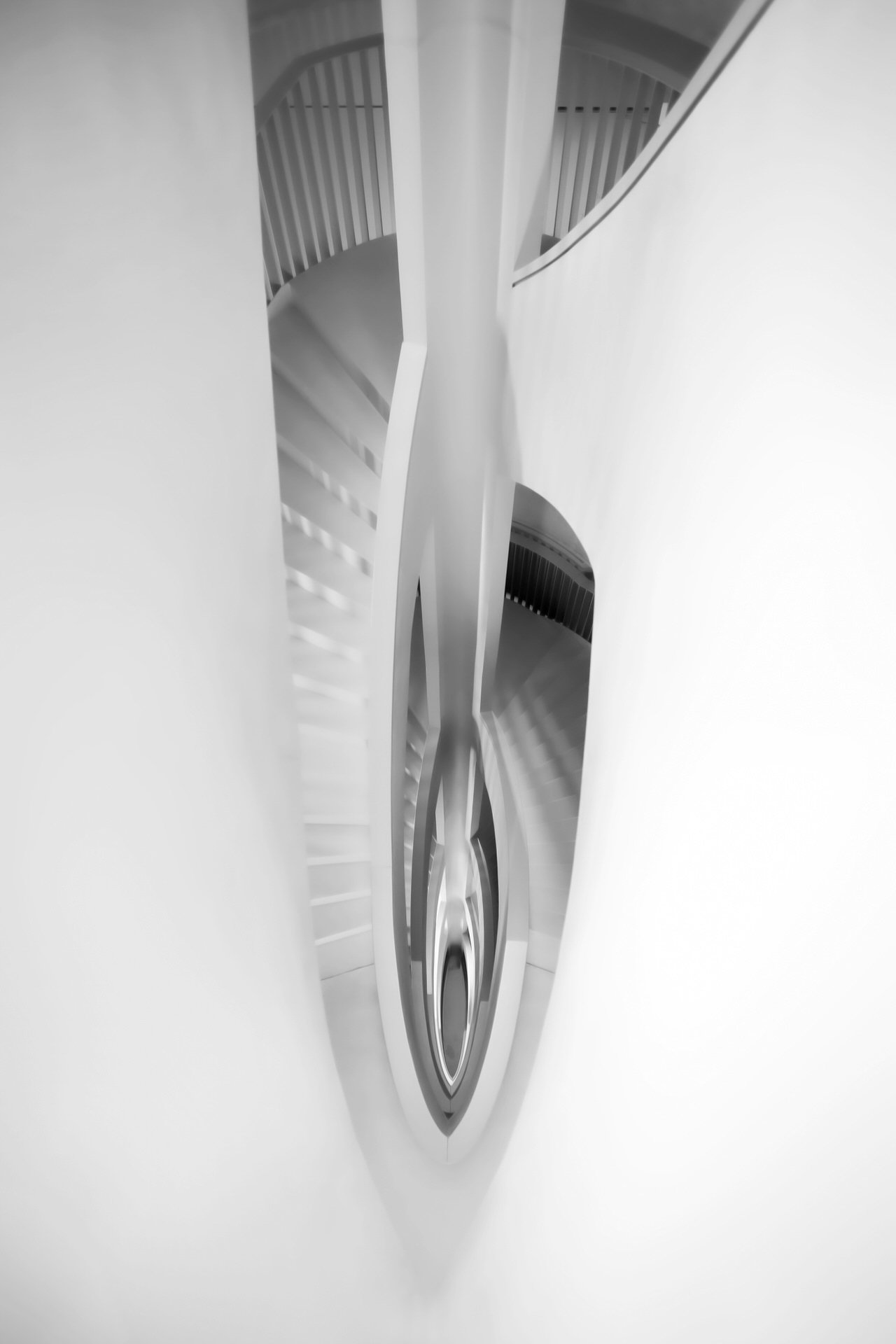 Abstract black-and-white photo of a spiral staircase viewed from above.