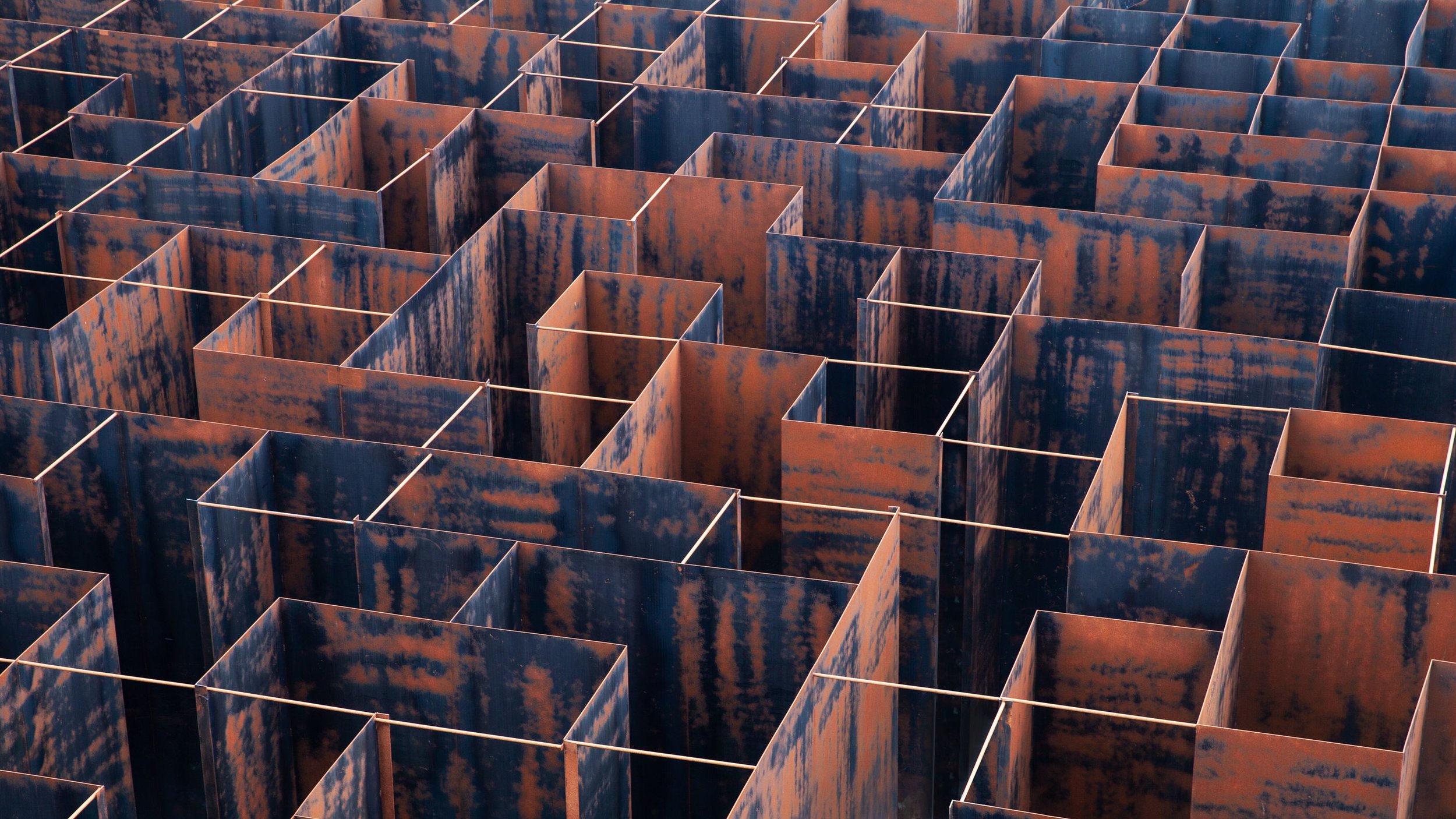A close-up image of a grid of rusted metal panels arranged vertically, creating a geometric pattern.