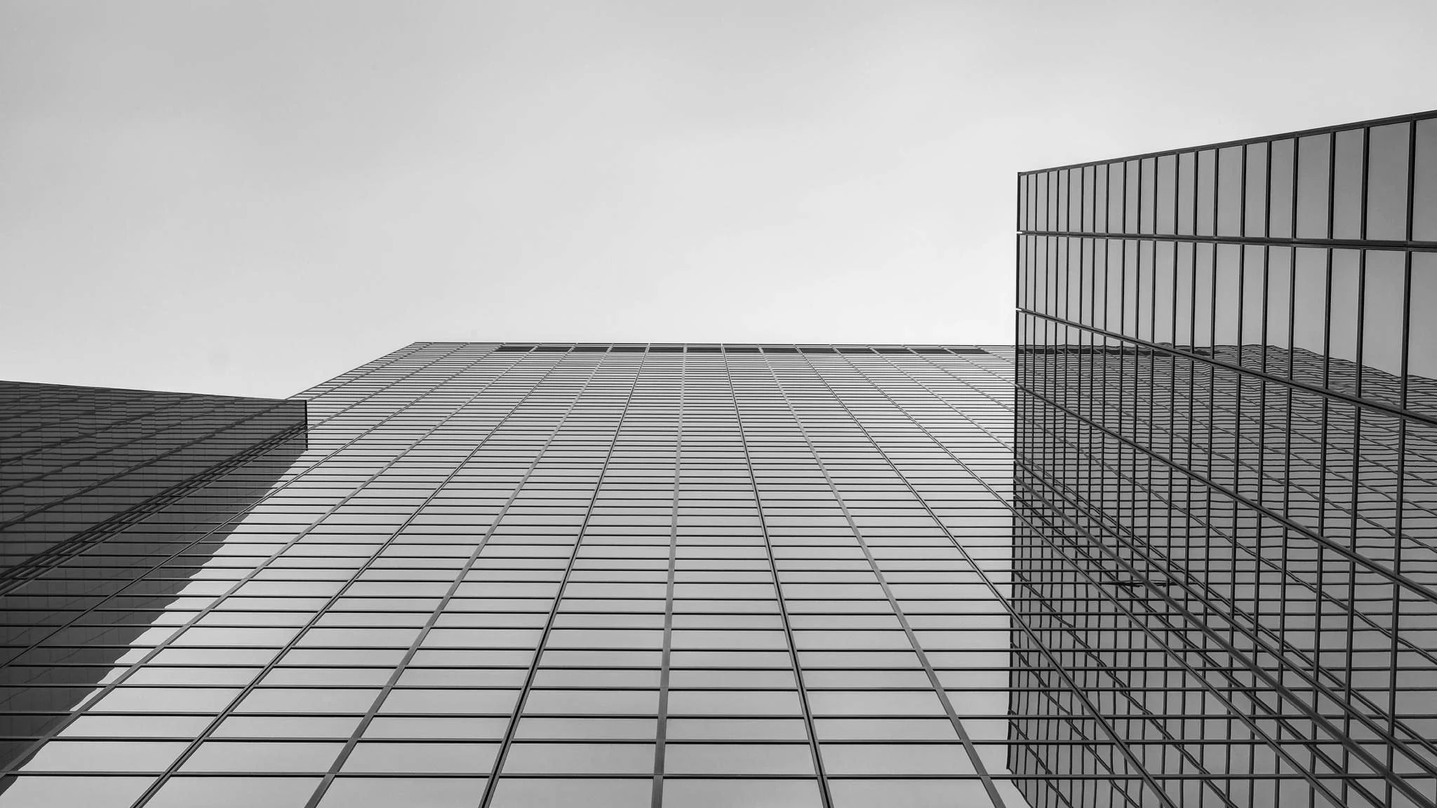 Low-angle view of modern glass skyscrapers with reflective windows against a cloudy sky.