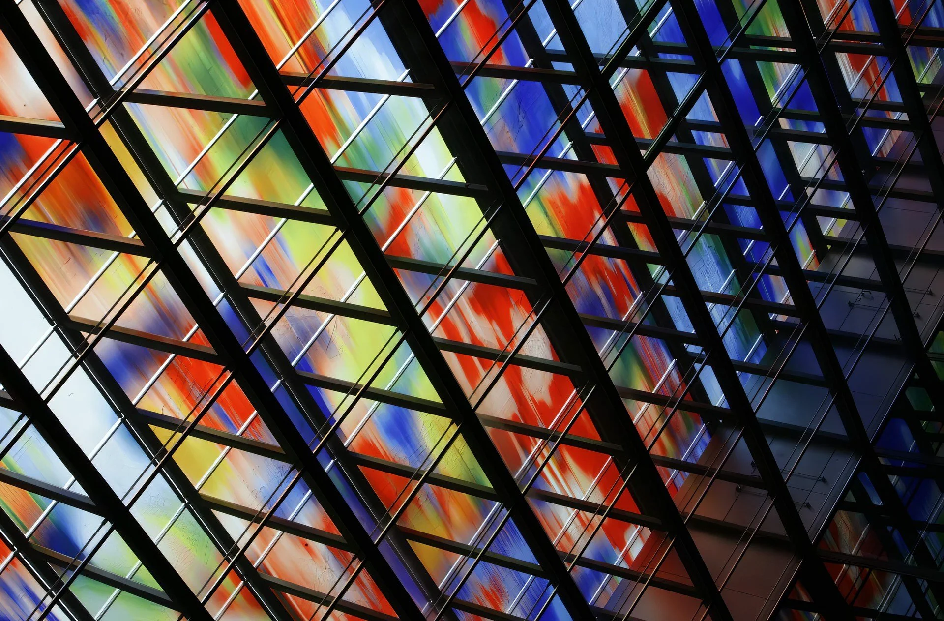 Close-up of a colorful stained-glass window with a black metal grid pattern.