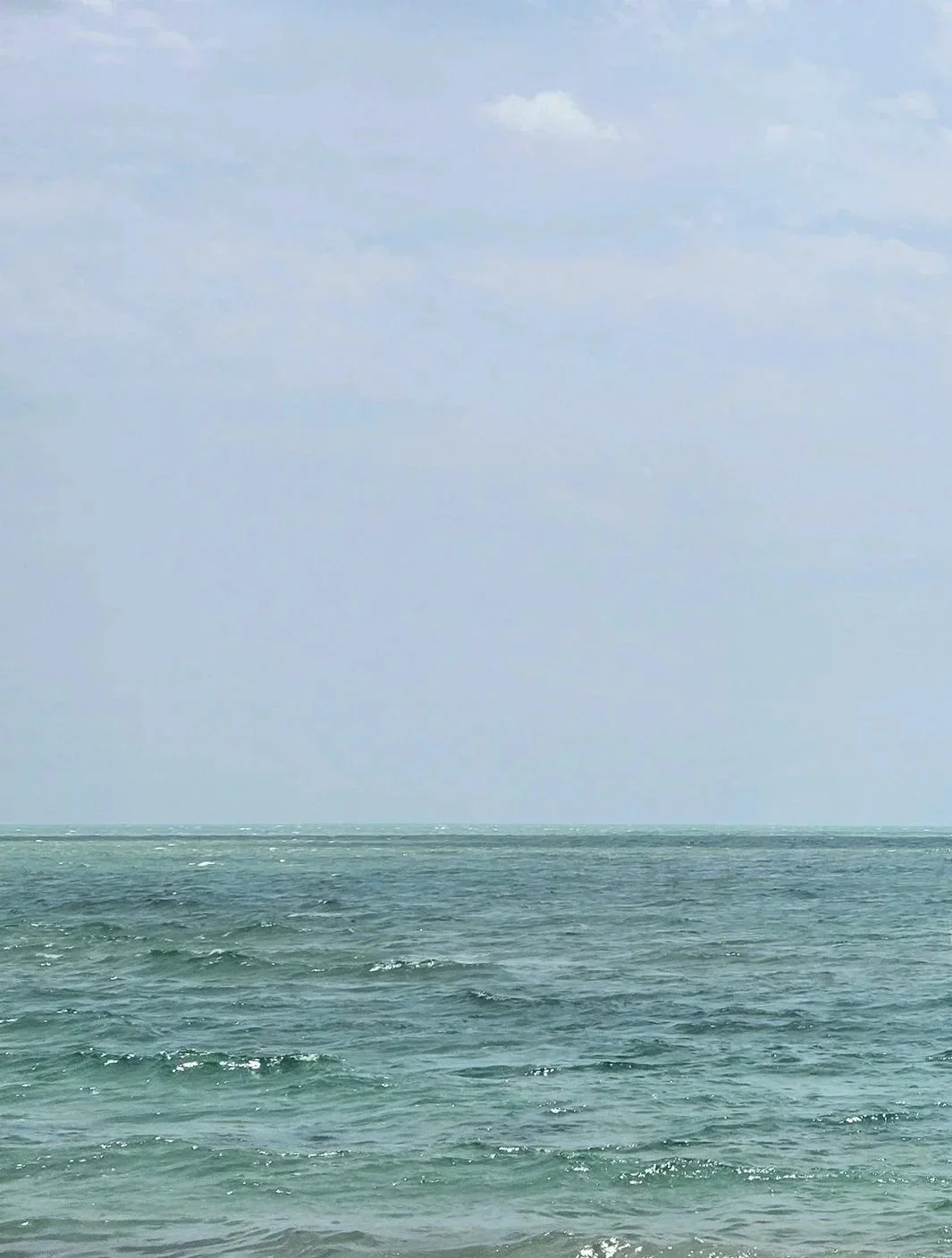 View of an ocean or sea with waves under a partly cloudy sky.