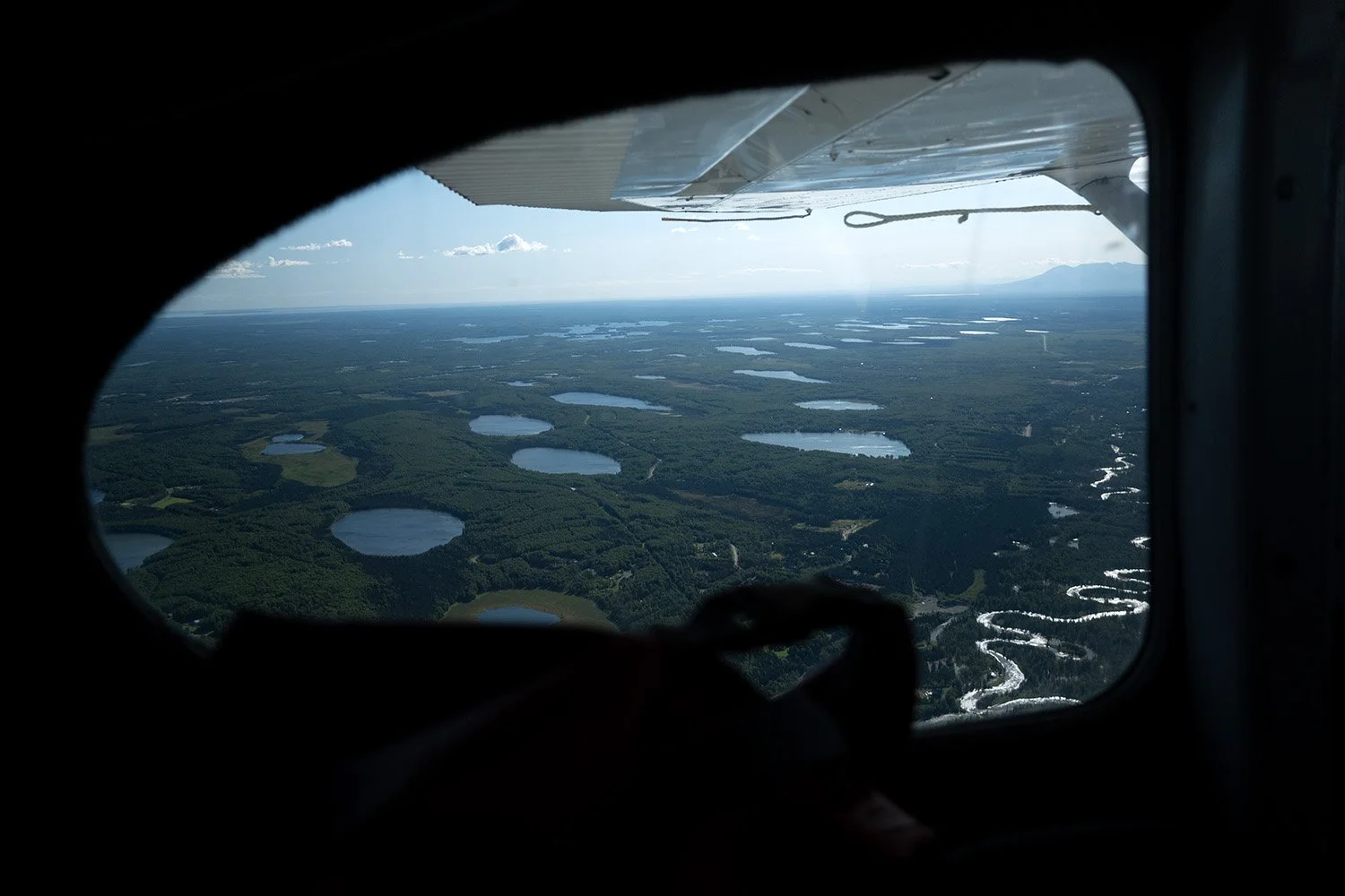 Aerial view of lakes and rivers seen through an airplane window.