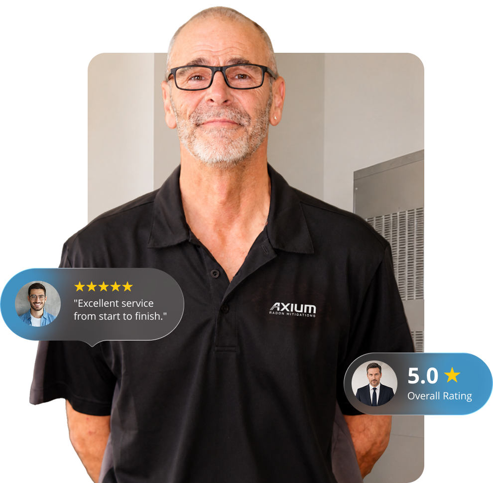 A middle-aged man with glasses, a beard, and earring, wearing a black polo shirt with 'AXIUM' logo, standing indoors with a neutral background.
