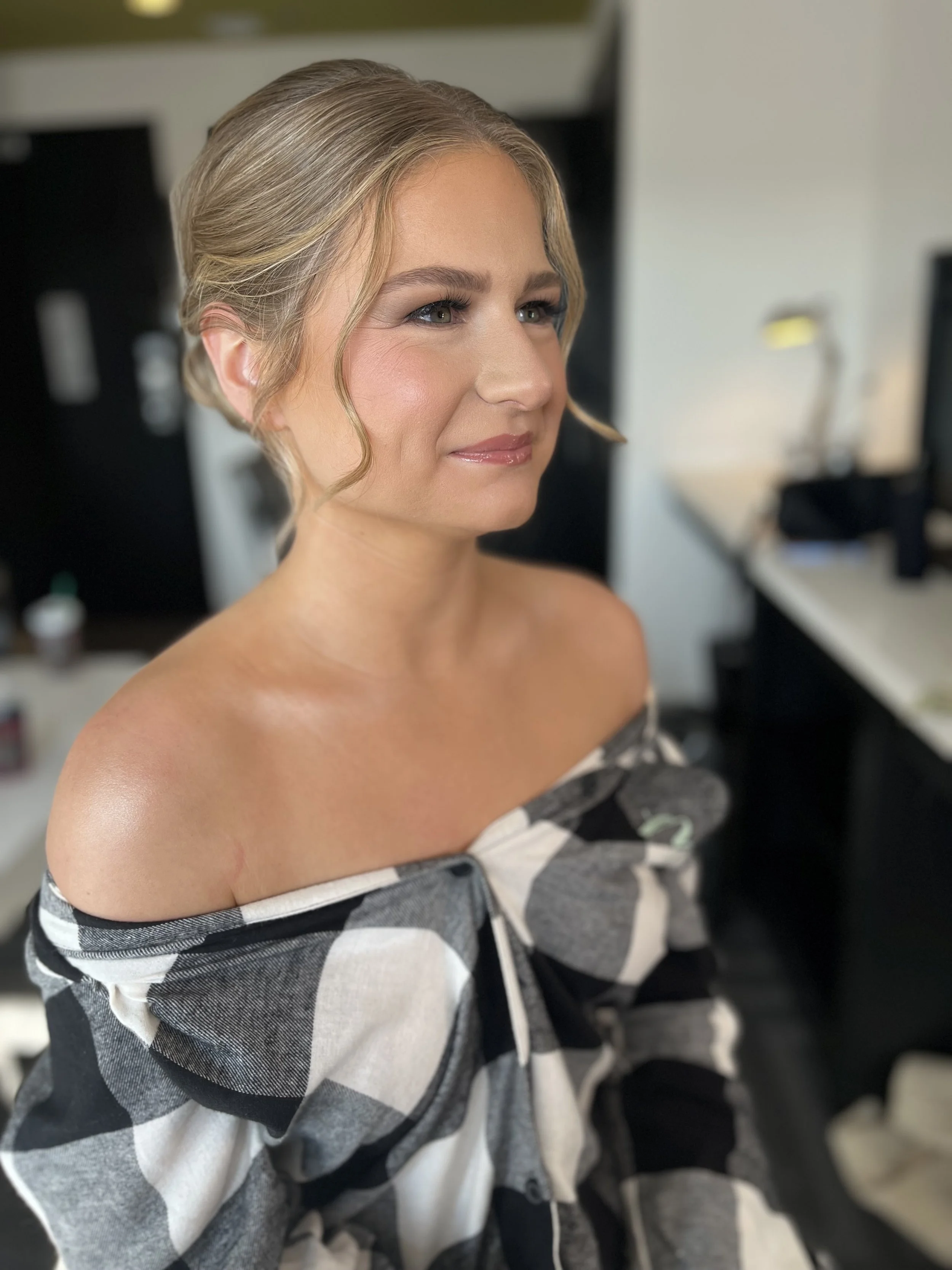 A woman wearing a white and black button up shirt posed for a photo after wedding makeup and hair