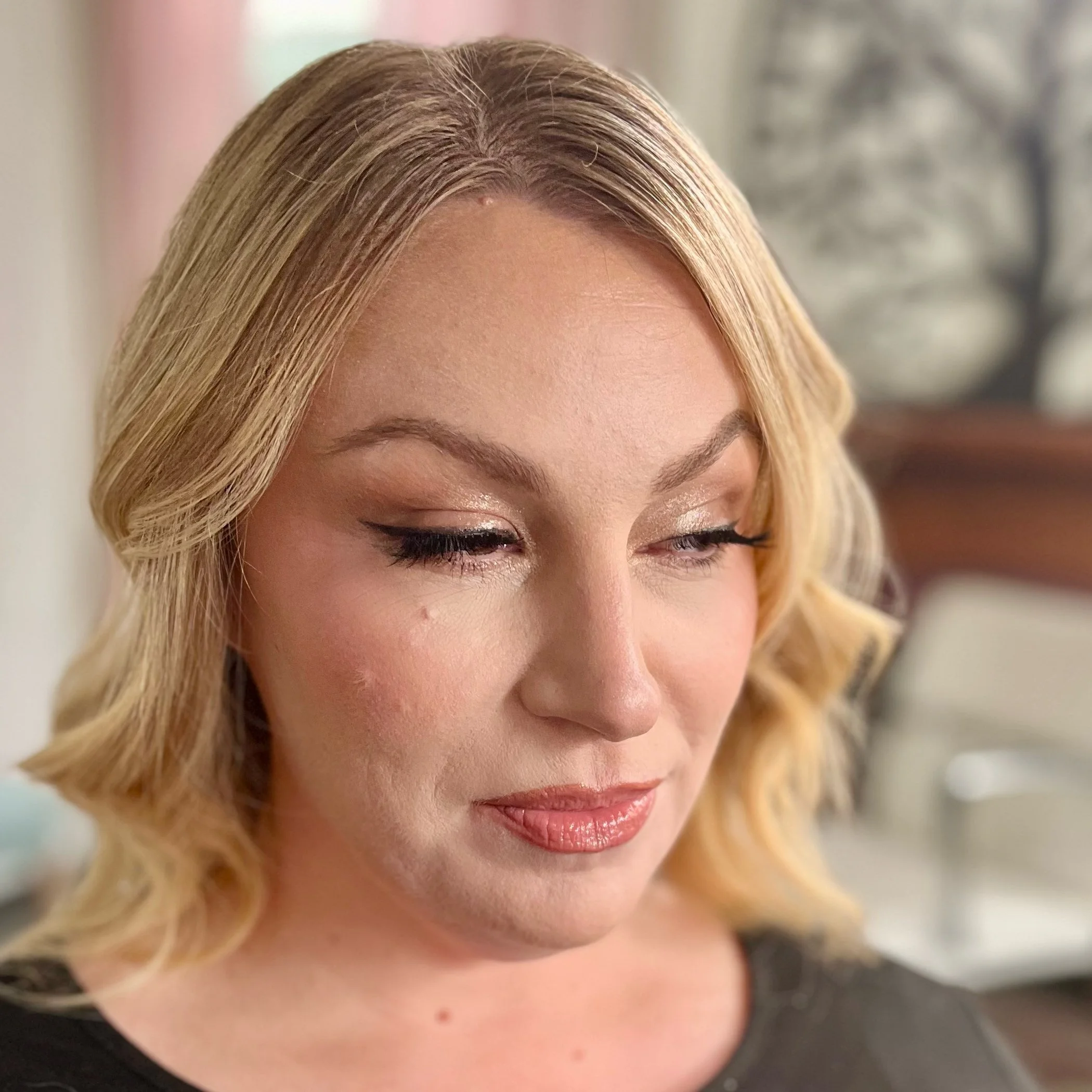 Close-up of a woman's face with blonde hair, makeup, and a focused expression.