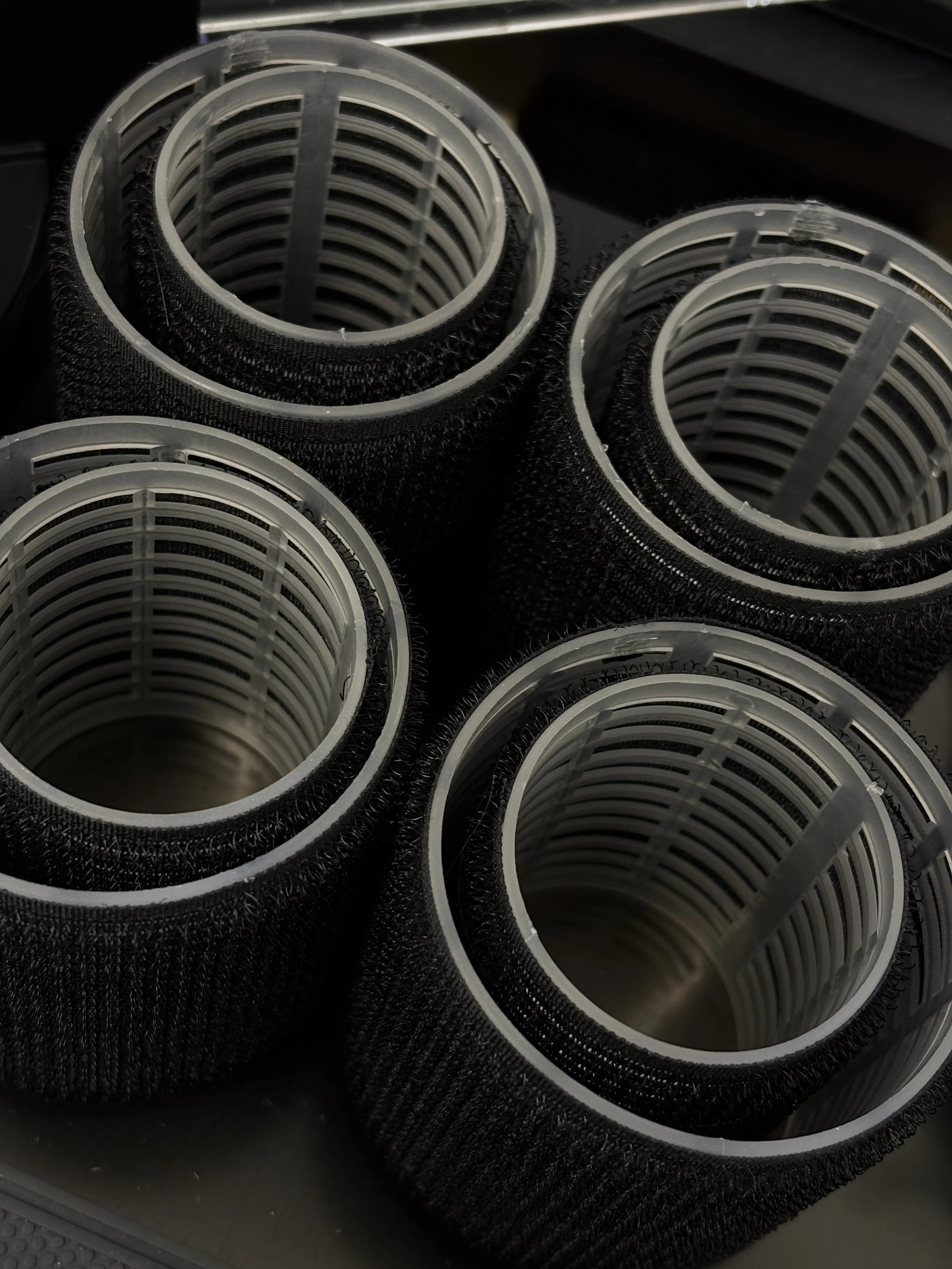 Close-up of several black cylindrical hair rollers, arranged in a group.