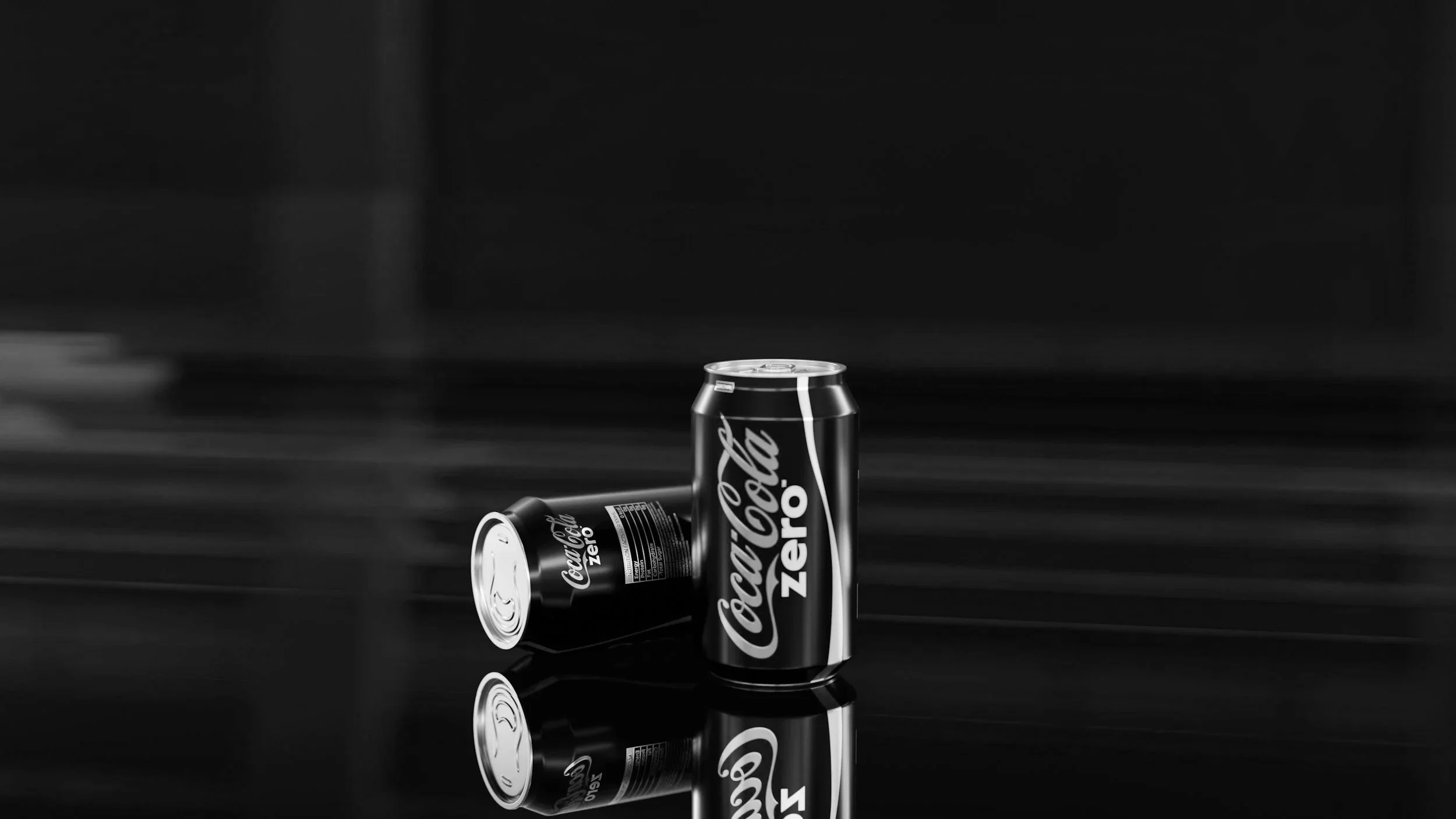 Black and white image of two cans of Coca-Cola Zero Sugar, with one can standing upright and another lying on its side, both on a reflective surface.