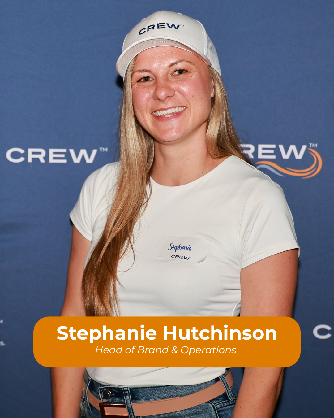 A woman wearing a white cap with 'CREW' written on it, a white t-shirt with a name tag, standing in front of a blue backdrop with 'CREW' logos.