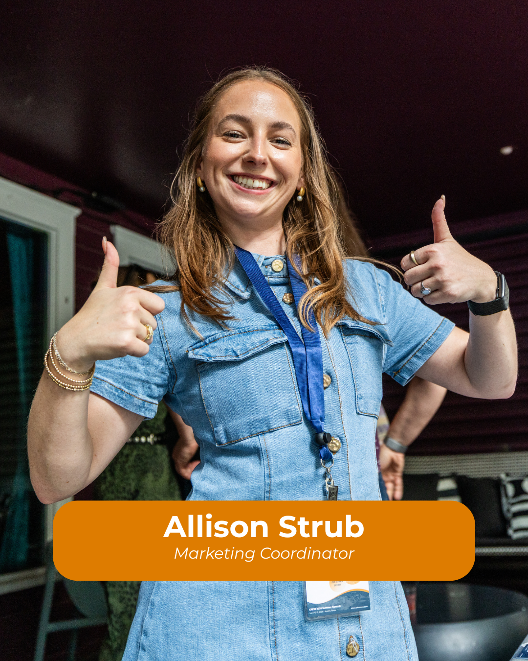 A woman smiling and giving two thumbs up, wearing a denim dress and a blue lanyard, with a name tag that reads Allison Strub, Marketing Coordinator.