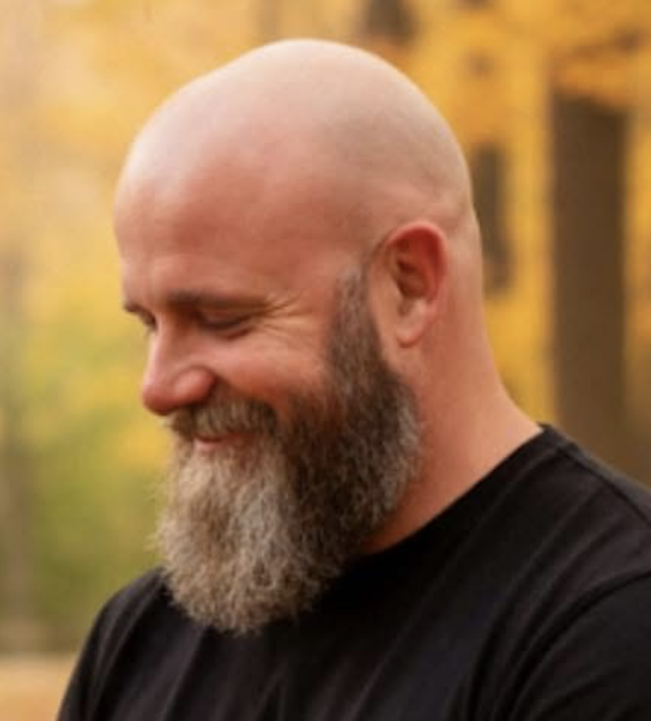 Gerald Cornwell outdoors, smiling with autumn trees in the background.