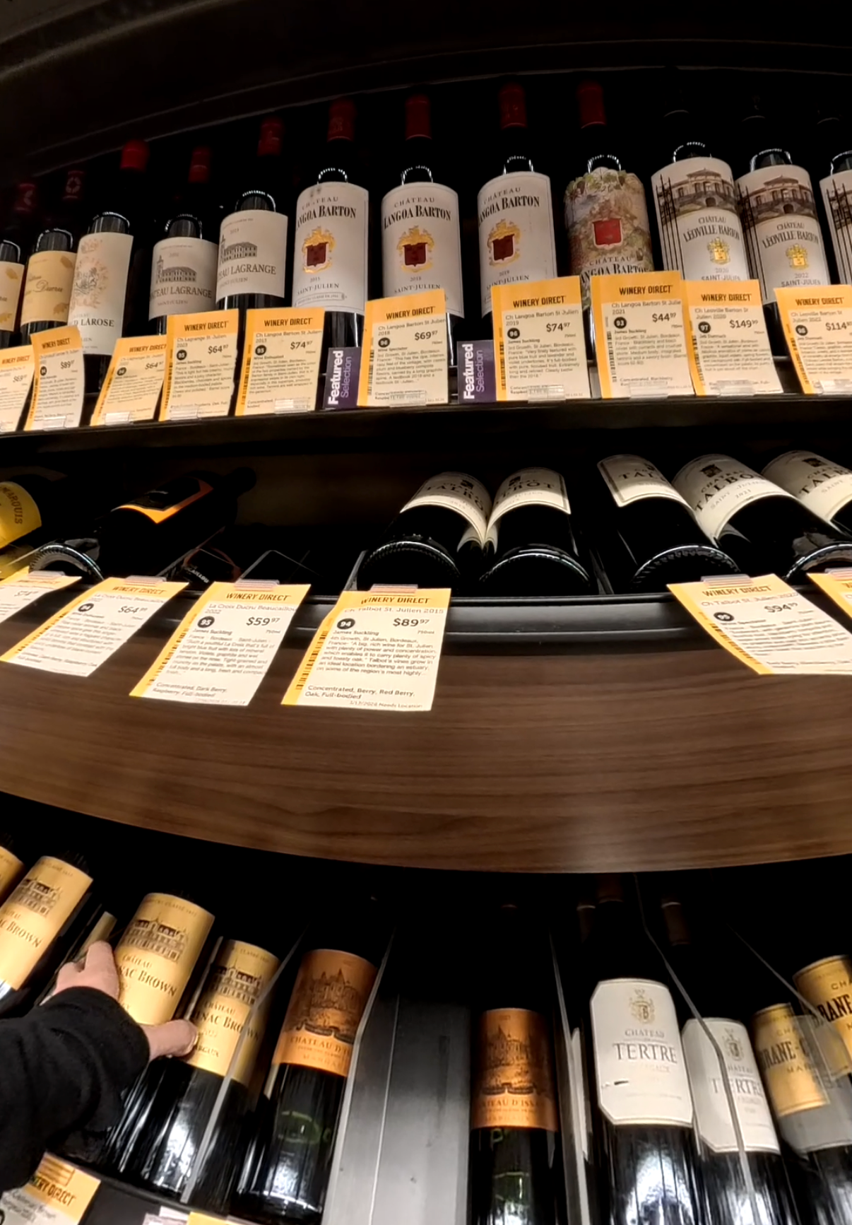 Shelf of wine bottles in a store, with labels and price tags visible.