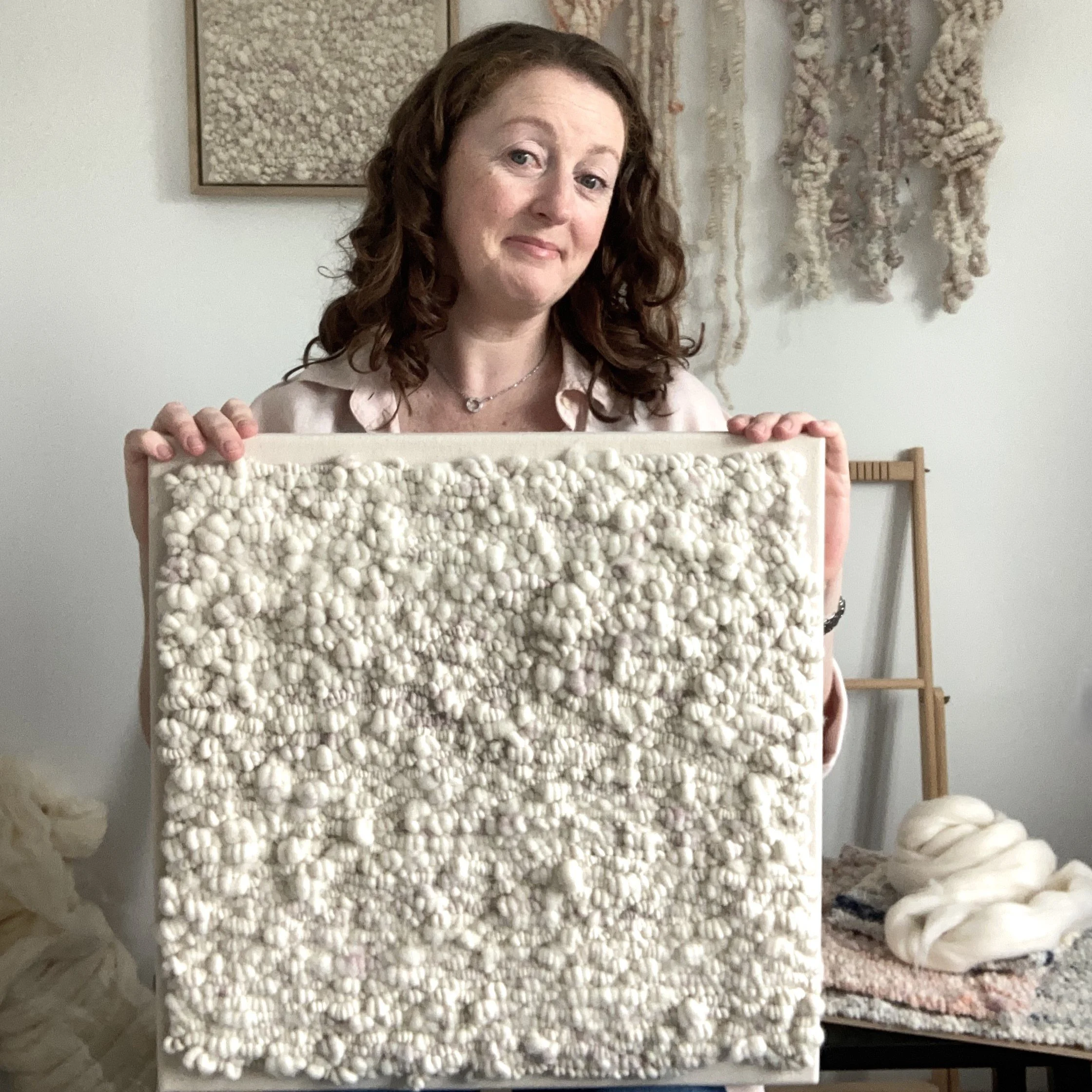 Image of textile artist Carol Matassa in her studio holding her artwork