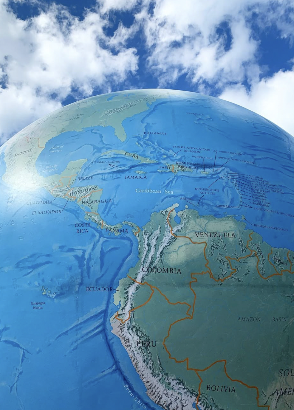 Decorative photograph taken by the author depicting a massive globe under a cloudy sky with the nation of Colombia in the center of the image