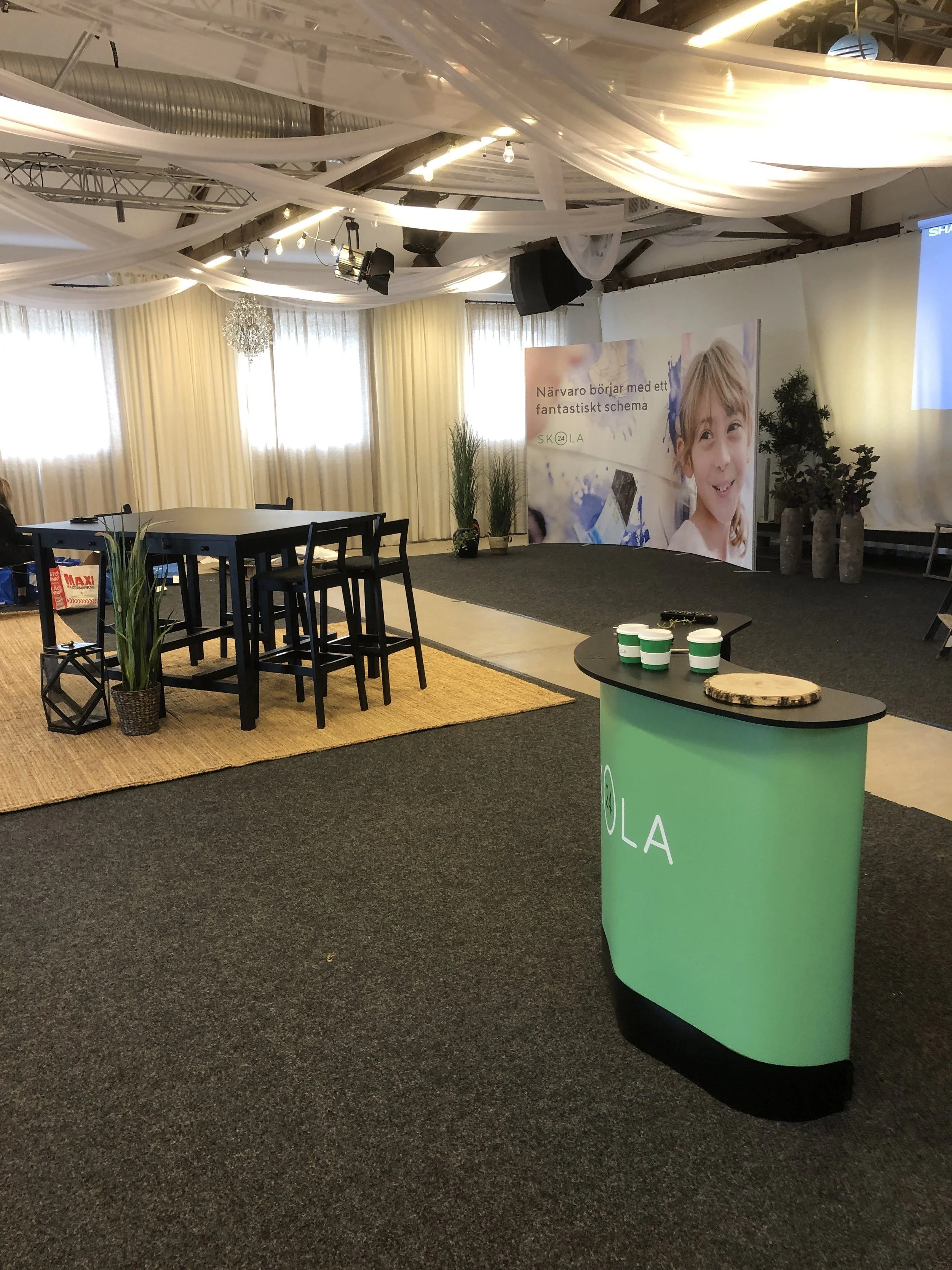 Mötes- och eventmiljö på Knista Herrgård med gröna växter, svarta bord och grön receptionsdisk.