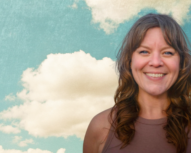 Aarde- Root Real Estate Broker smiling outdoors with a blue sky and clouds in the background.