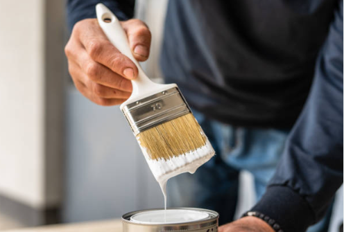 Person painting with a brush on a can of paint.