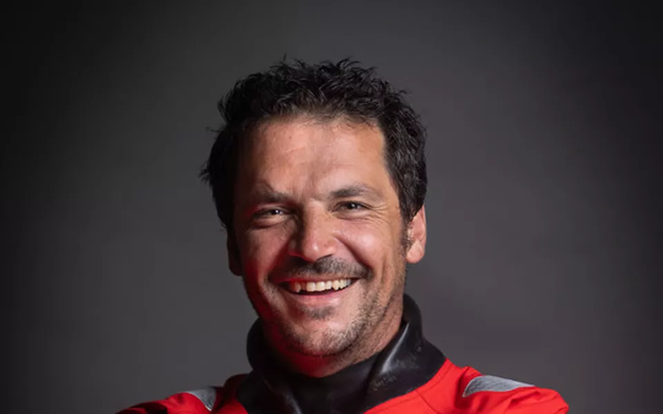 Hommes souriant portant des vêtements de sport rouges et noirs contre un fond gris